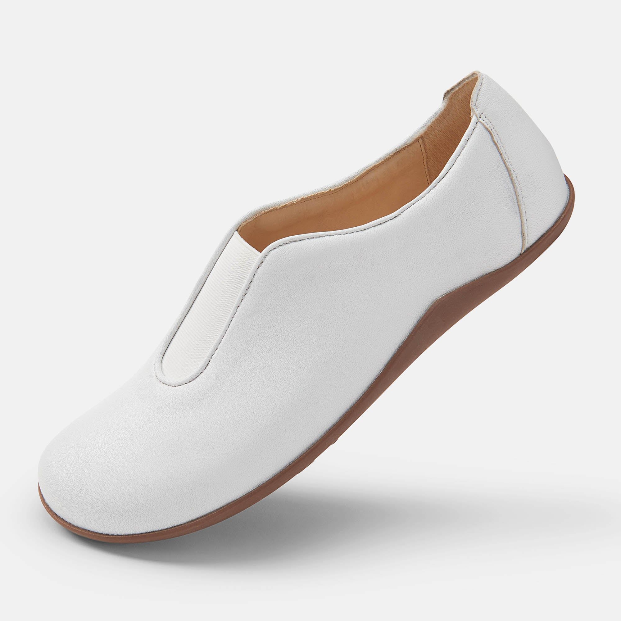 Weißer Slipper mit brauner Sohle. Schuh von der Seite, leicht schräg.