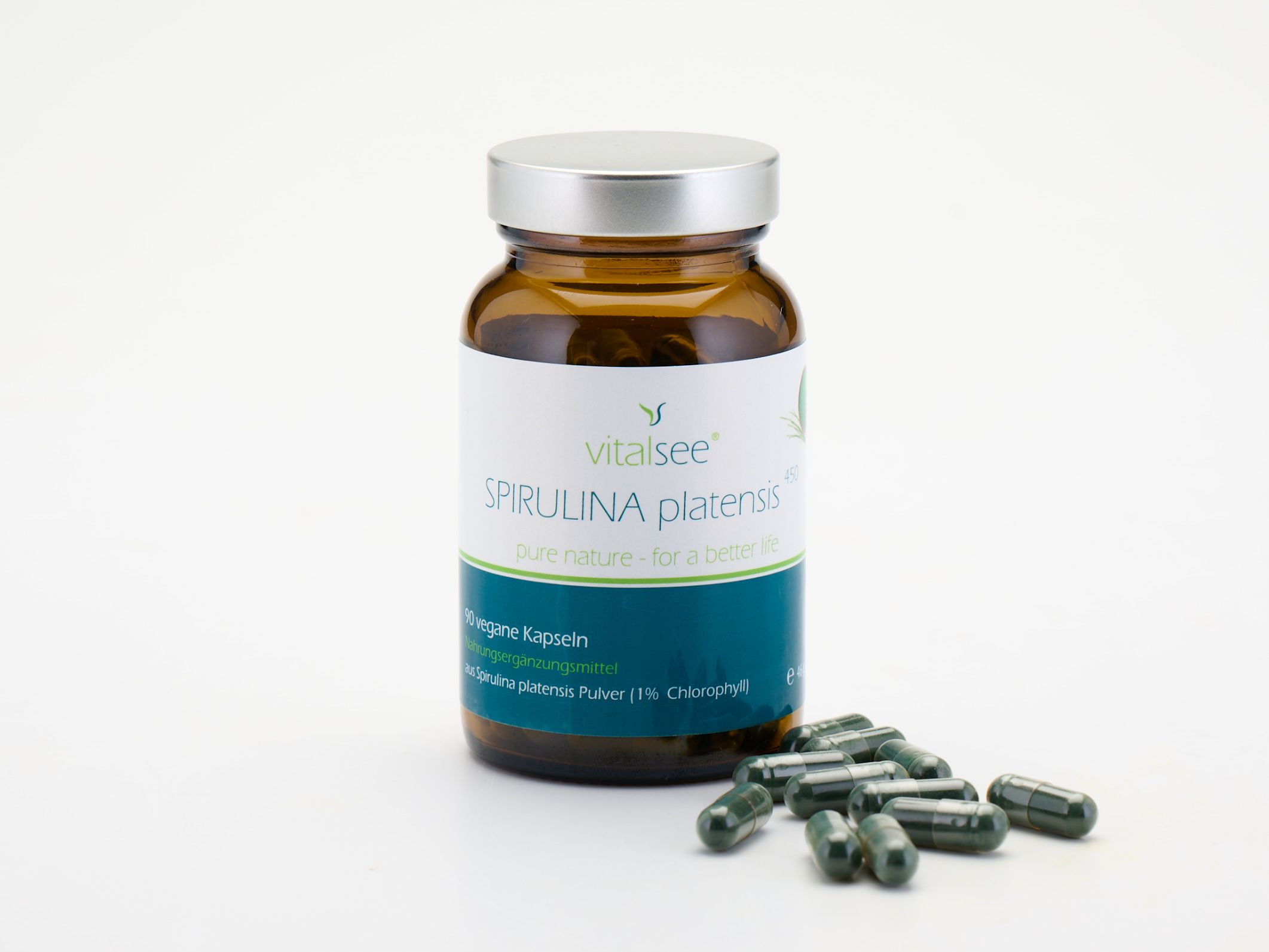 Braune Glasflasche mit Kapseln daneben. Etikett mit "Vitalsee SPIRULINA platensis". Vegan.