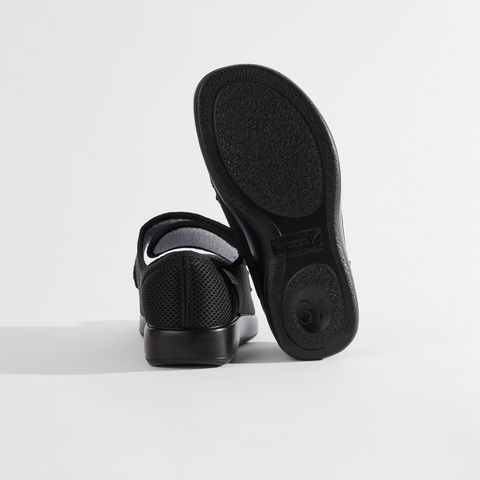 Schwarze Sandale mit Klettverschluss und Mesh-Obermaterial.