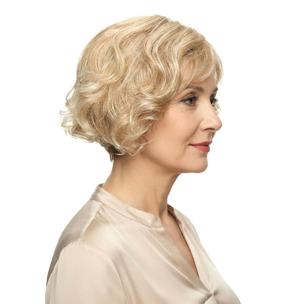 Blonde Perücke mit Pony, welligem Haar. Frau im Profil, beiges Oberteil.