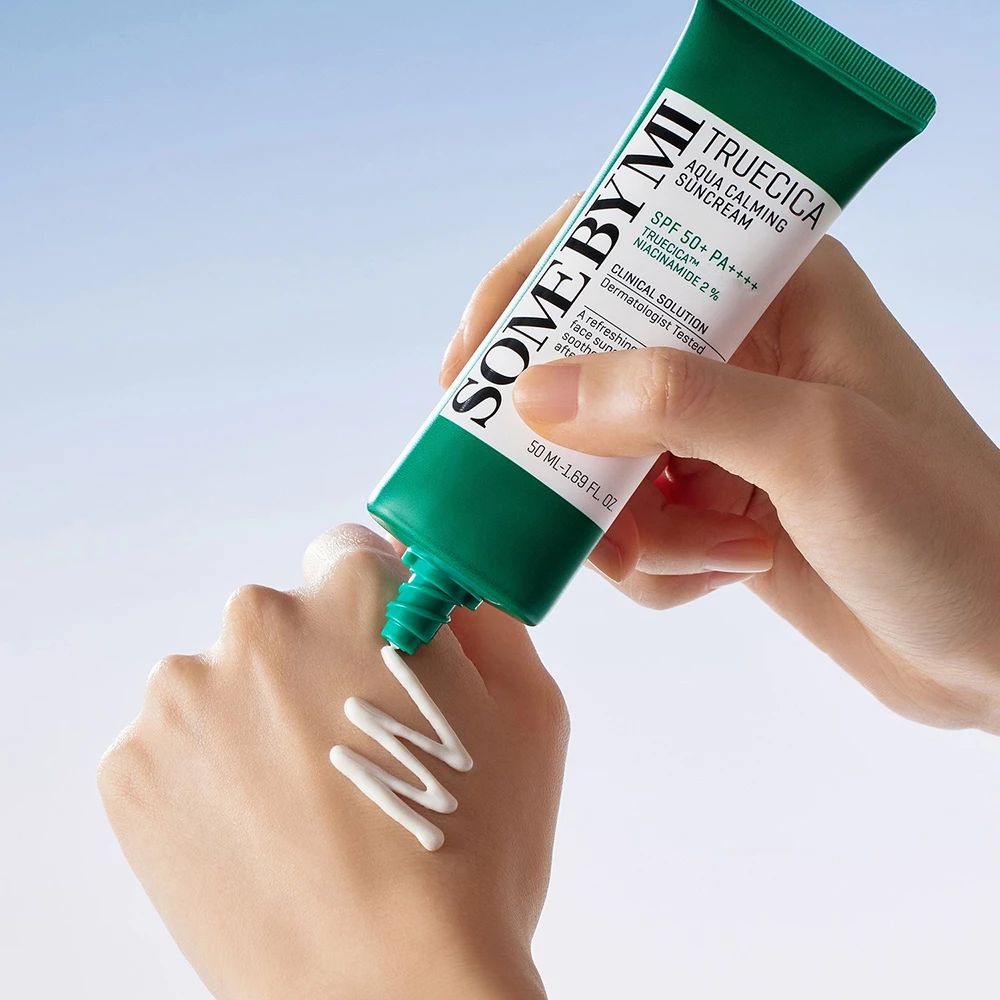 Hand drückt Sonnencreme aus grüner Tube. Text: SOMEBYMI, Truecica Aqua Calming Suncream, SPF 50+ PA++++.