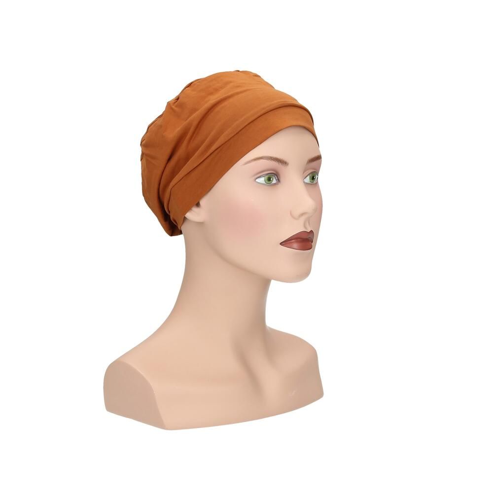 Ockerfarbener Turban auf einer Schaufensterpuppe. Schräge Frontansicht. Stoff mit Falten. Für Kopfbedeckung.