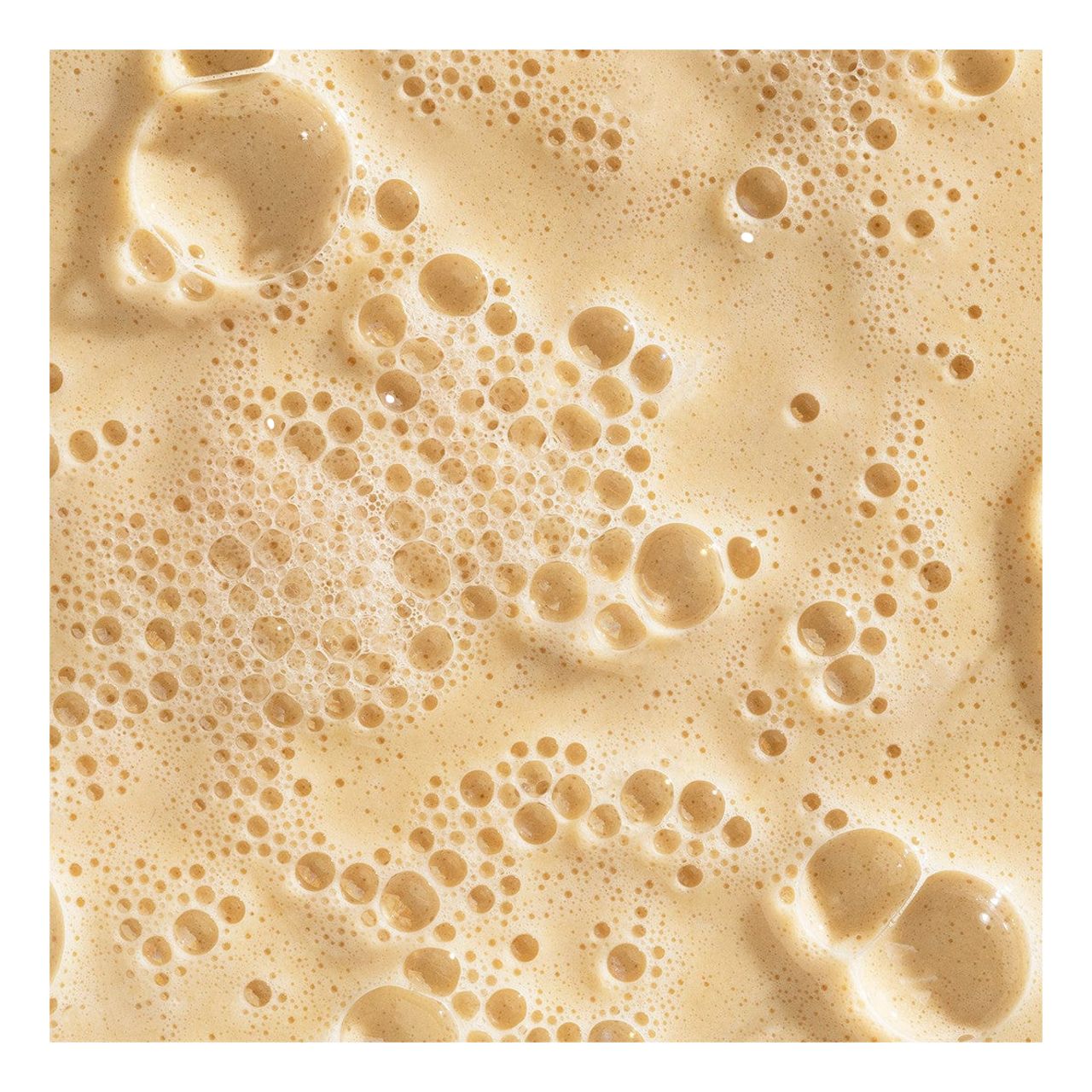 Nahaufnahme von cremiger, schäumender Flüssigkeit mit Blasen unterschiedlicher Größe.