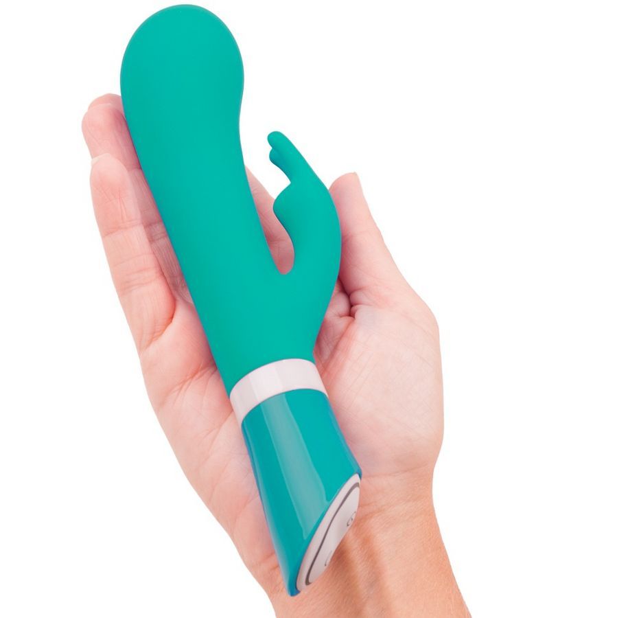 Grüner Silikonvibrator in einer Hand. Der Vibrator hat eine gebogene Form und eine Kaninchenform.