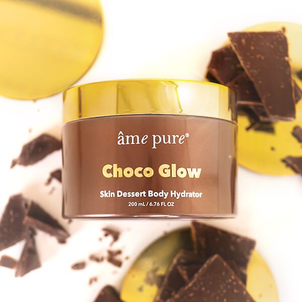 Bruine pot met gouden deksel. Opschrift: âme pure Choco Glow Skin Dessert Body Hydrator. Met stukjes chocolade.