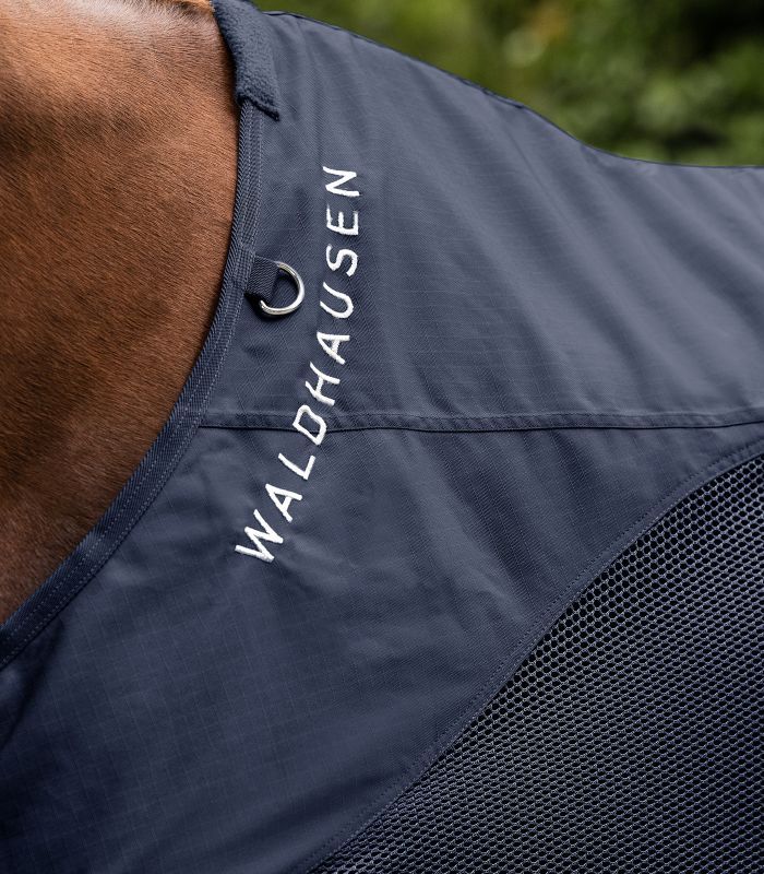 Nahaufnahme der Pferdedecke. Dunkelblau mit weißem Schriftzug "WALDHAUSEN". Netzgewebe am Halsbereich.