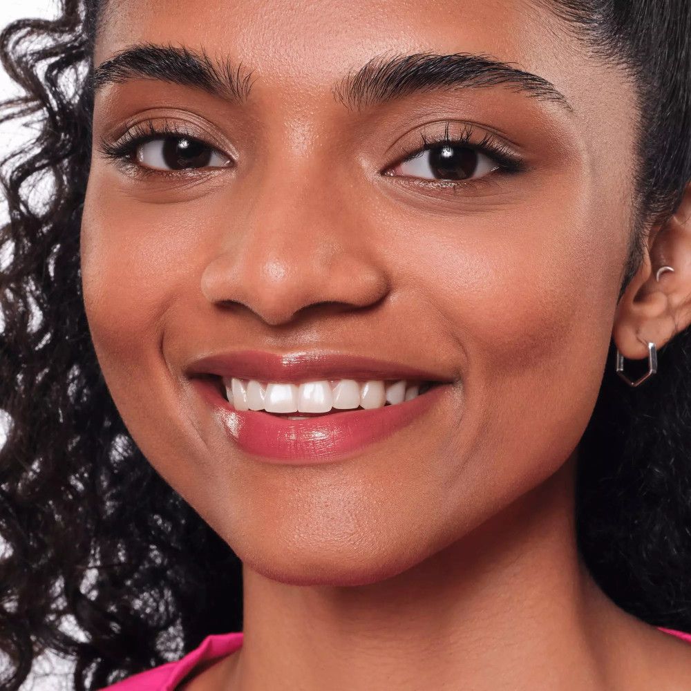 Porträt einer Frau mit rosa Lippen. Sie lächelt. Ohrringe.