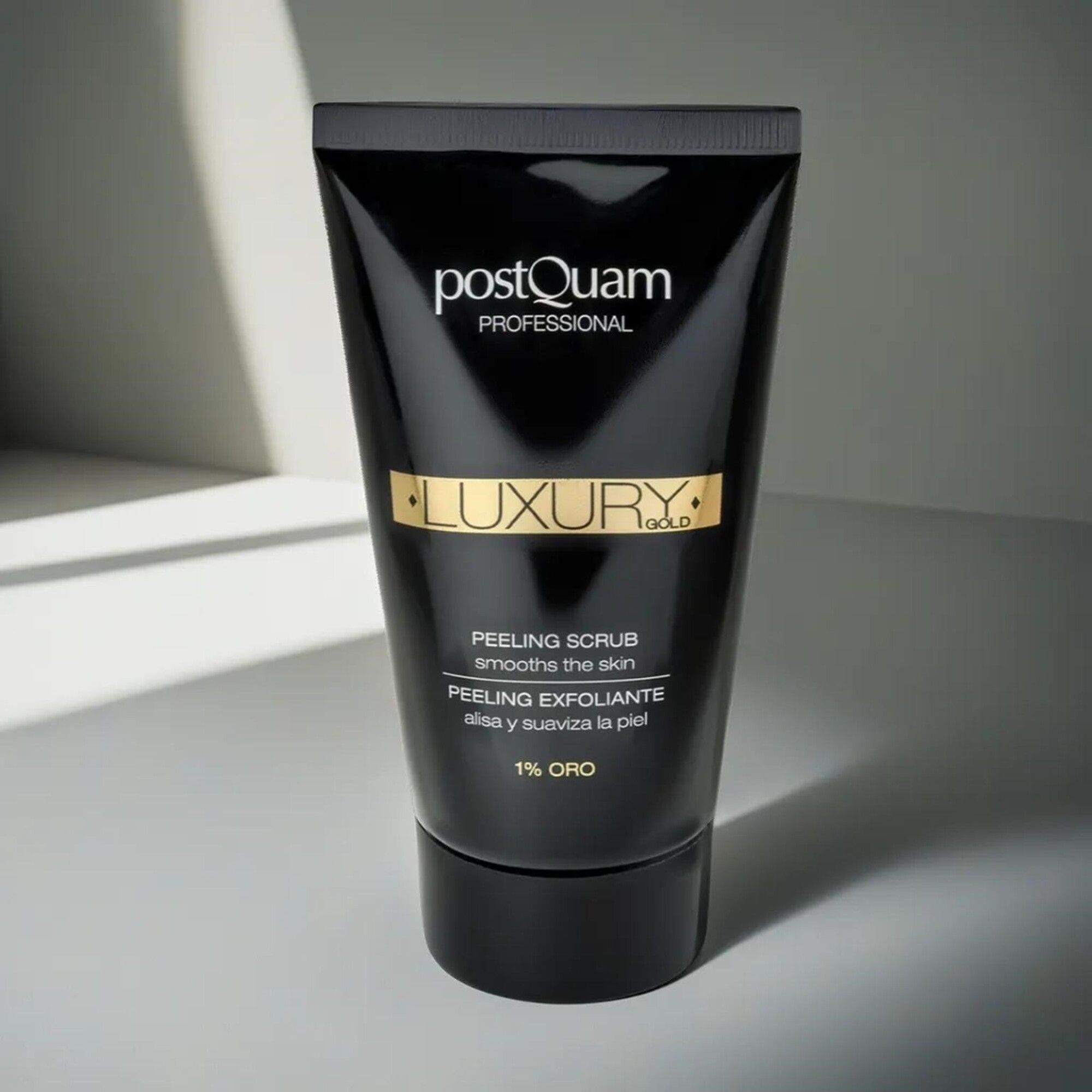 Schwarze Tube "Postquam Professional Luxury Gold". Text: Peeling Scrub, 1% Oro. Schwarzer Deckel. Auf hellem Hintergrund.