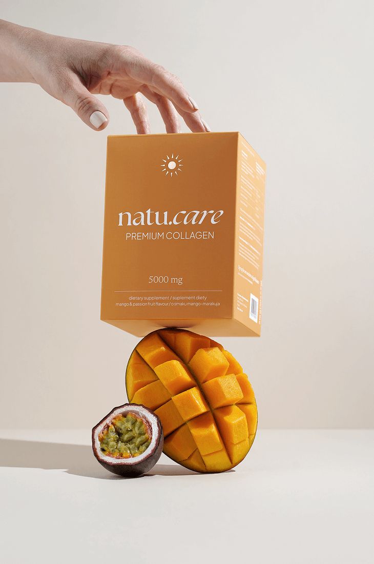 Produktbox und Mango-Maracuja-Hälfte. Box mit Premium Collagen. Eine Hand hält die Box über Früchten.