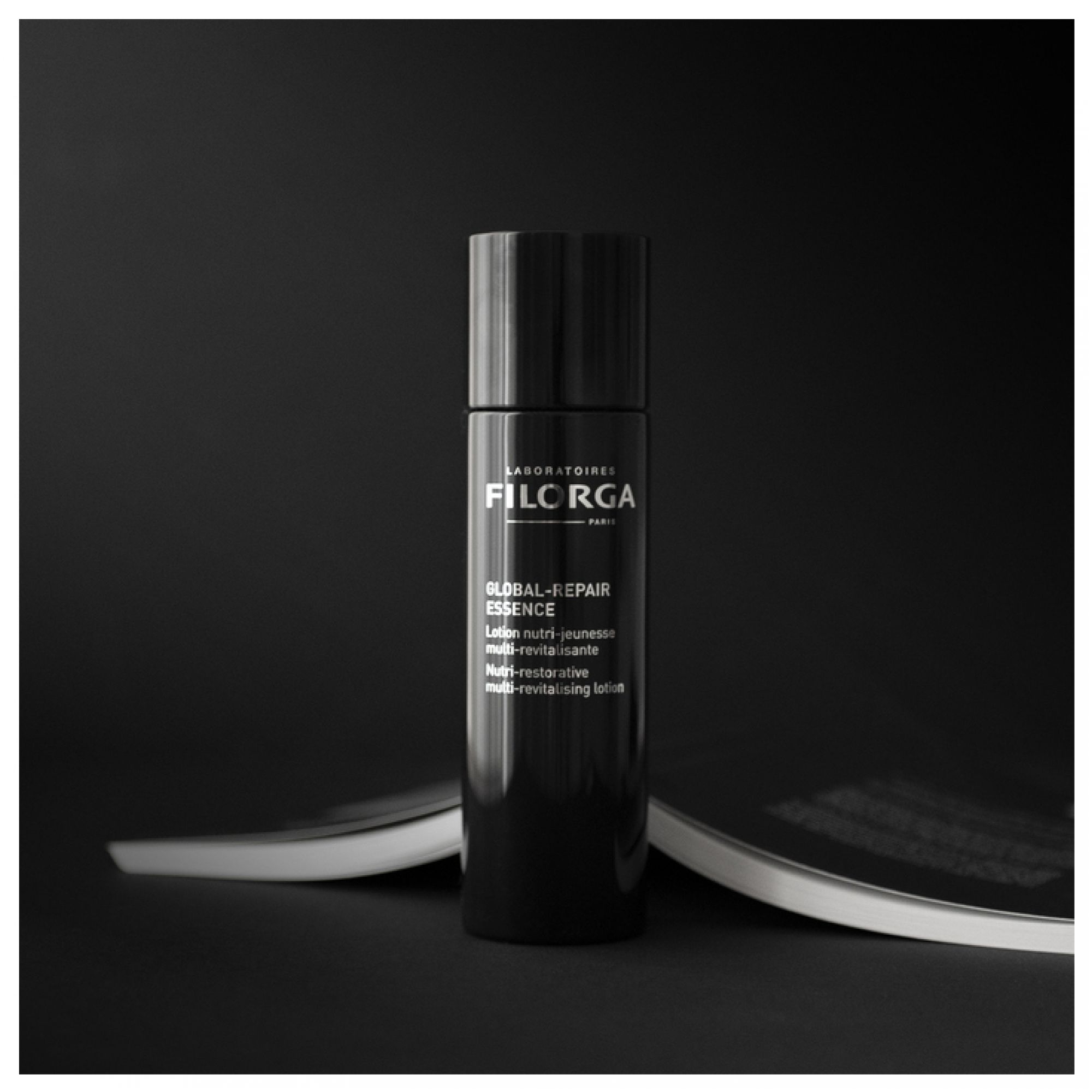Schwarze Flasche FILORGA GLOBAL-REPAIR ESSENCE auf dunklem Hintergrund.