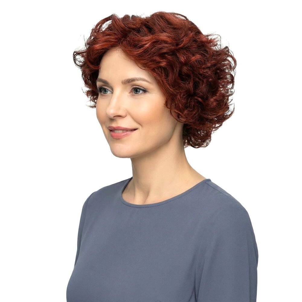 Frau mit roter, lockiger Perücke. Seitenansicht. Kurzes, voluminöses Haar. Bluse in Blau. Weißer Hintergrund.