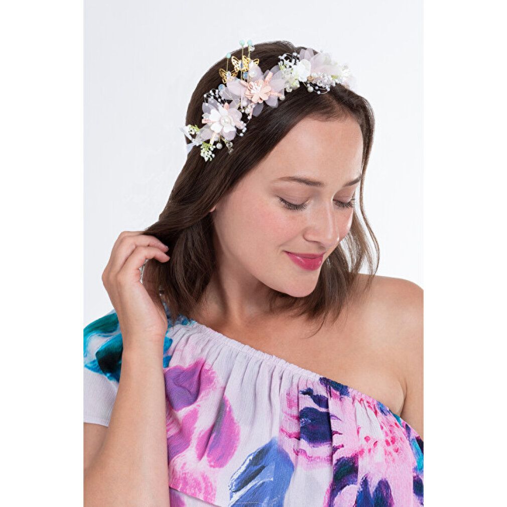 Blumenstirnband mit Blüten und Blättern. Die Frau trägt ein Kleid mit floralem Muster. Nahaufnahme, vor weißem Hintergrund.