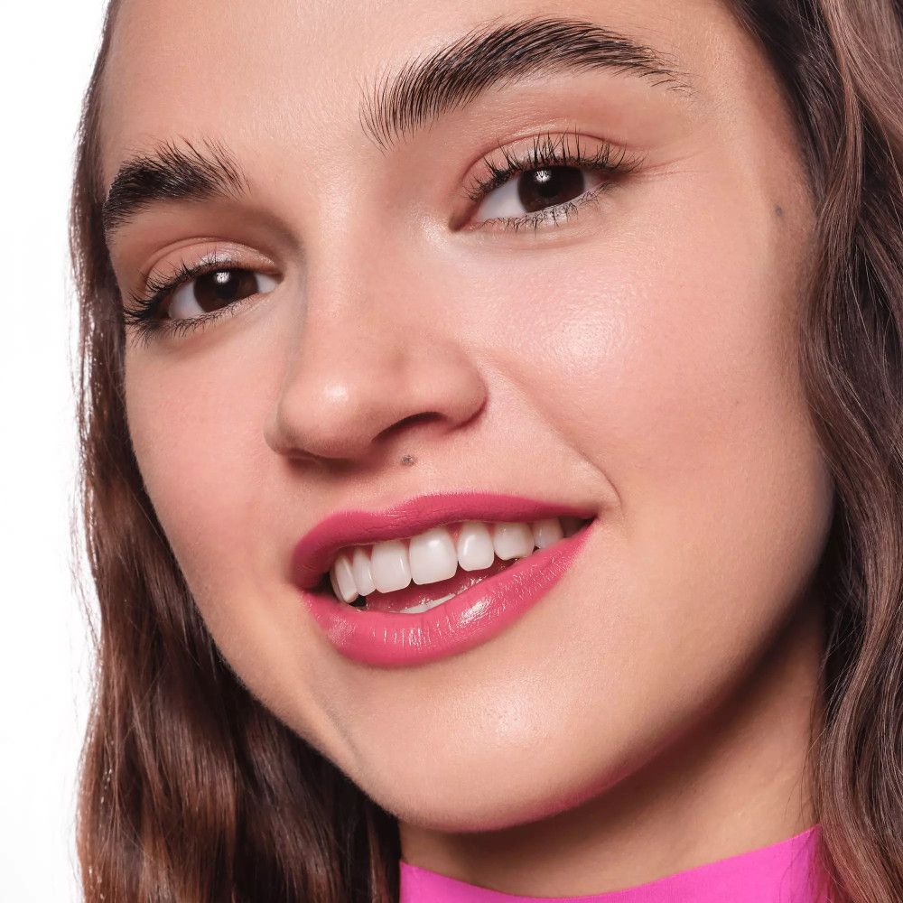 Porträt einer Frau mit rosa Lippenstift. Sie lächelt und zeigt Zähne.