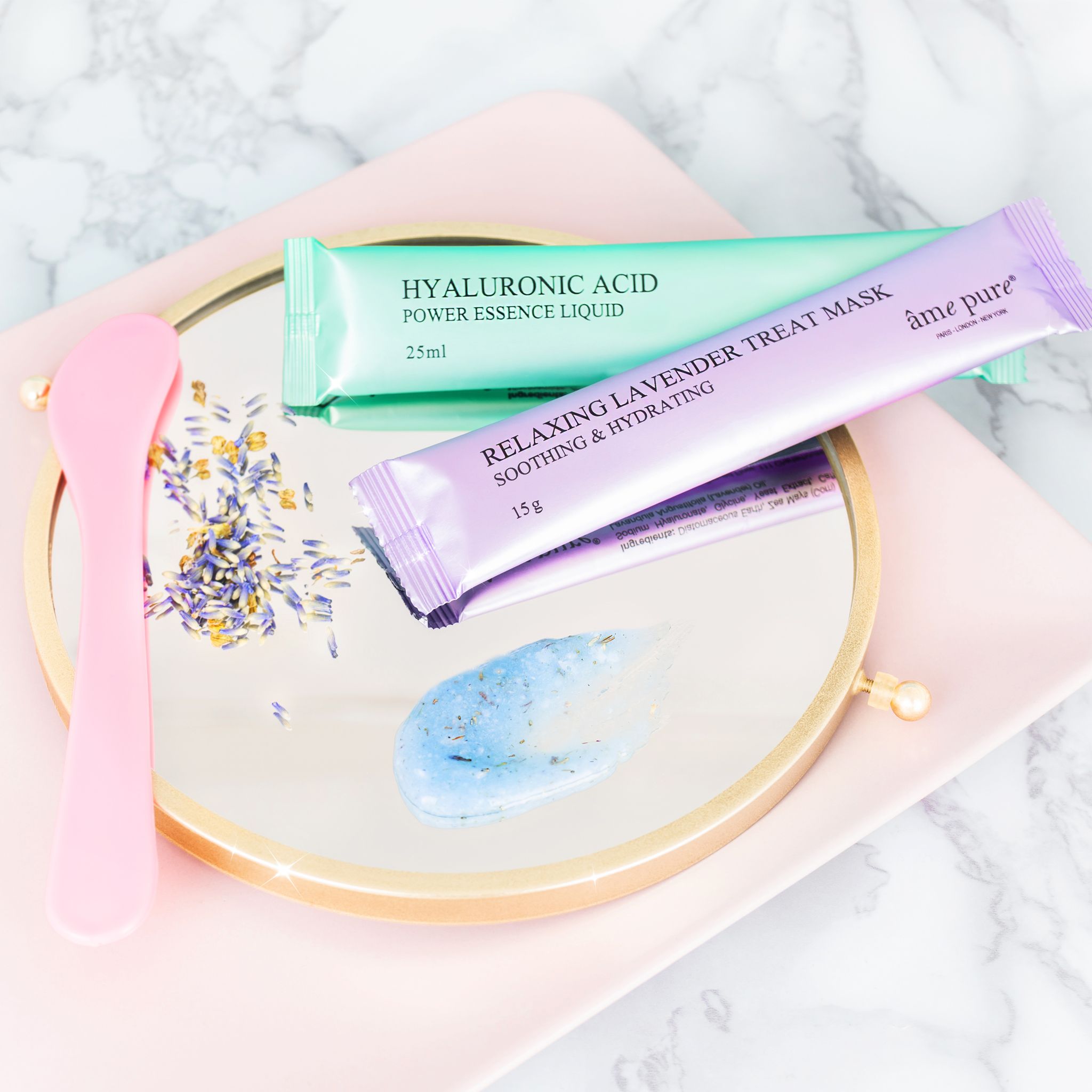 Spiegel met zakjes, spatel en maskerresten. Zakjes: Hyaluronic Acid, 25ml. Relaxing Lavender Treat Mask, 15g. Roze spatel.