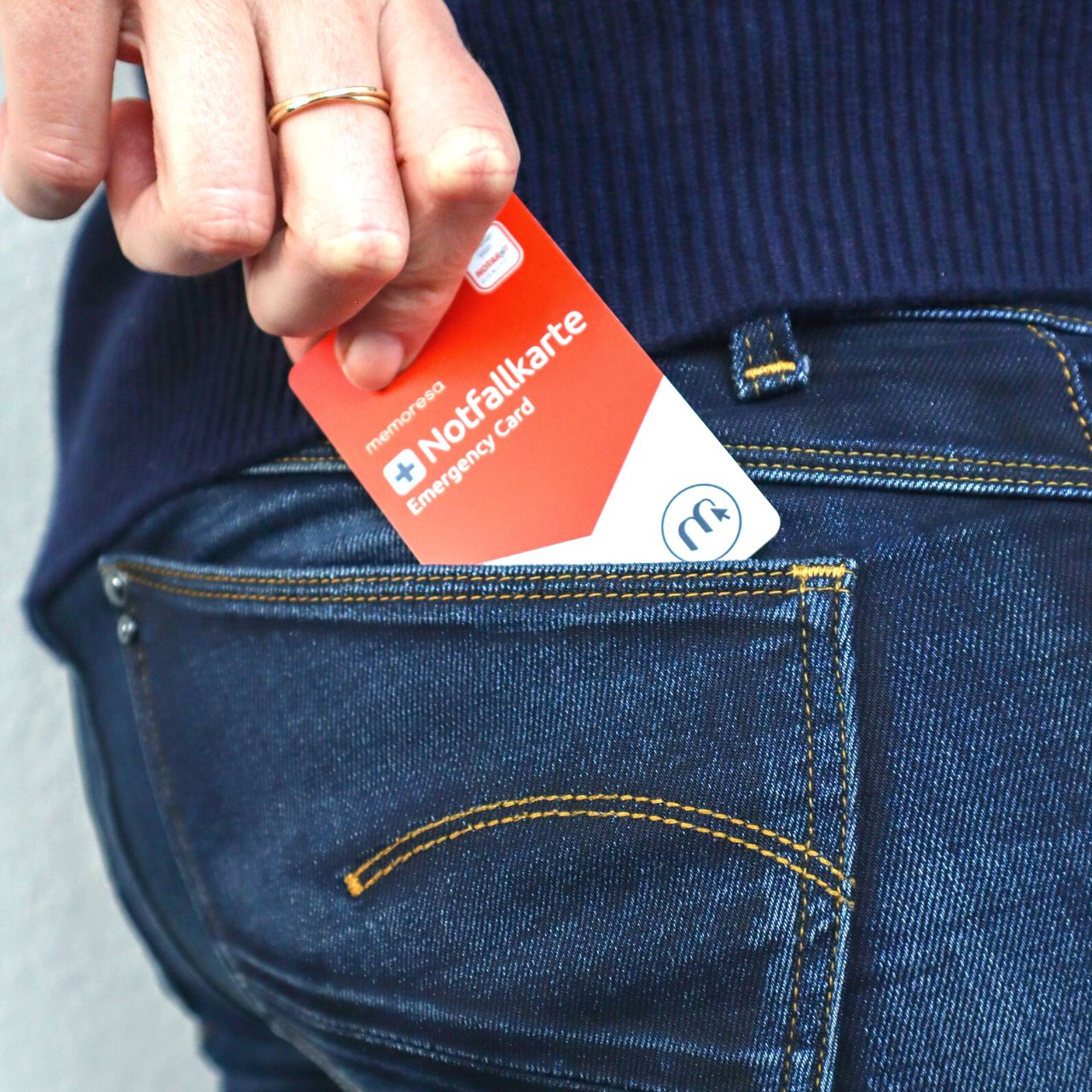 Notfallkarte wird aus Jeans-Tasche gezogen. Rote Karte mit weißem Bereich und Logo.