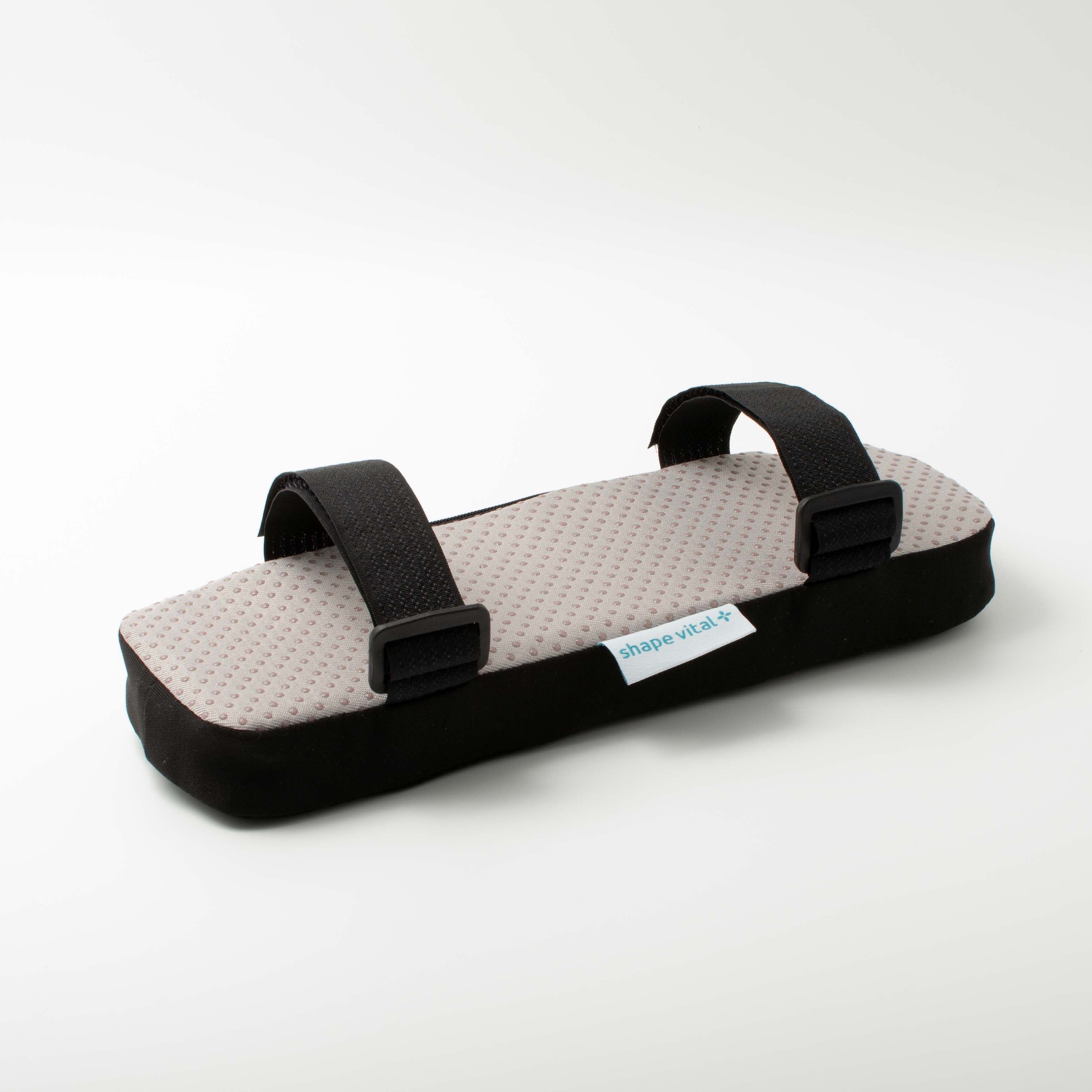 Armlehnenkissen mit grauer, genoppter Oberfläche und schwarzem Rand. Schwarze Gurte mit Clips. Etikett 'shape vital+'.