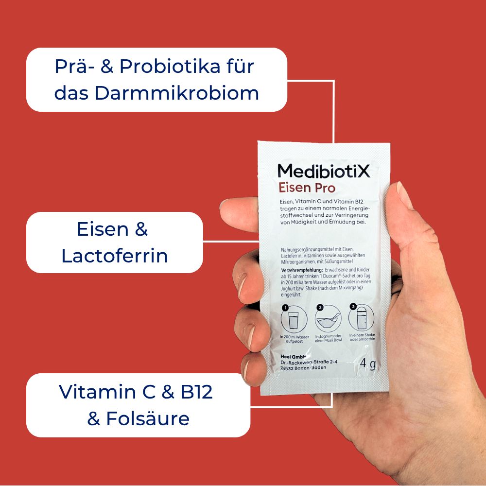 Hand hält MedibiotiX Eisen Pro-Beutel. Beutel mit Produktnamen und Inhaltsangaben. Hintergrund rot.