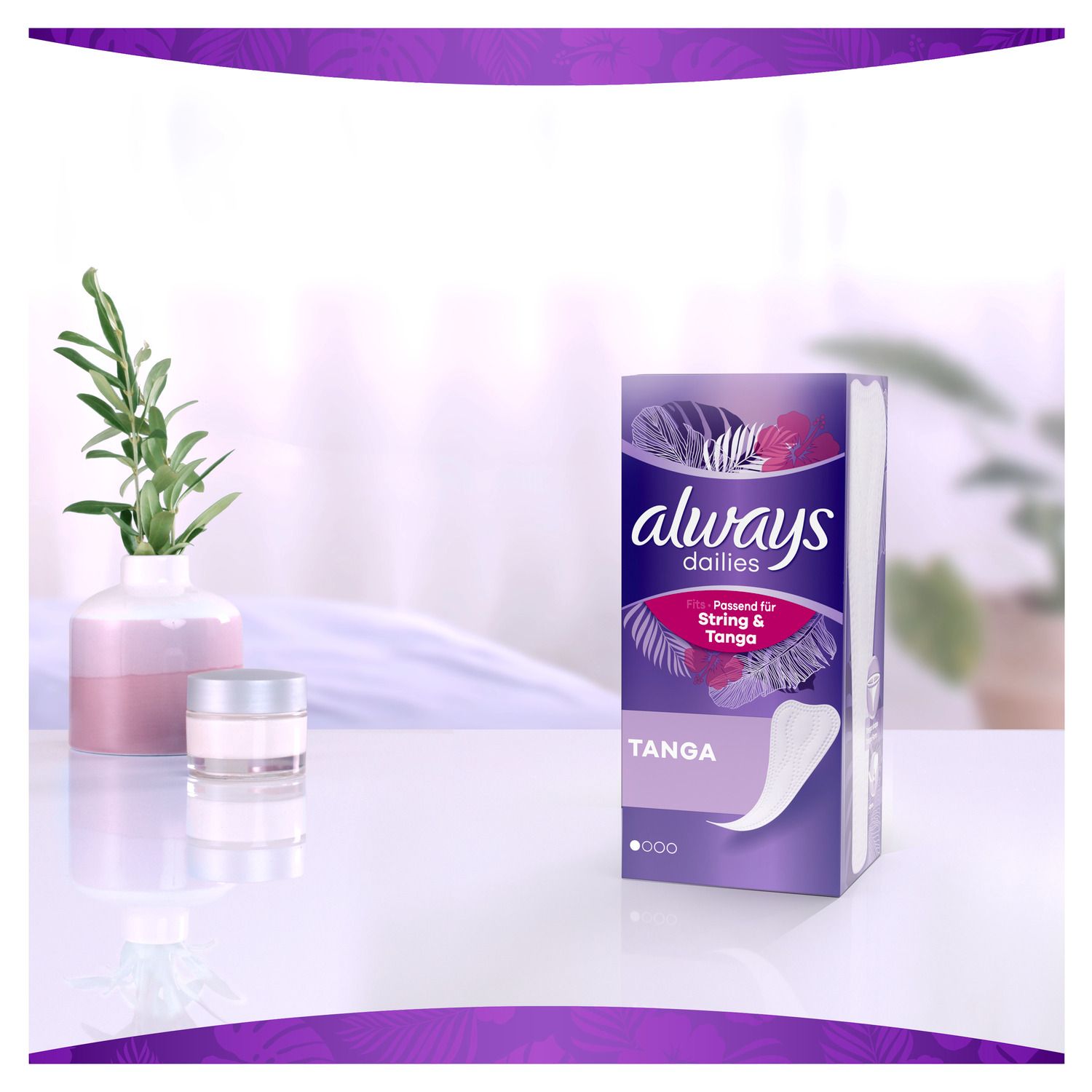 Always Dailies Slipeinlagen Tanga auf Tisch. Lila Verpackung, daneben Vase mit Pflanze und Creme-Tiegel.