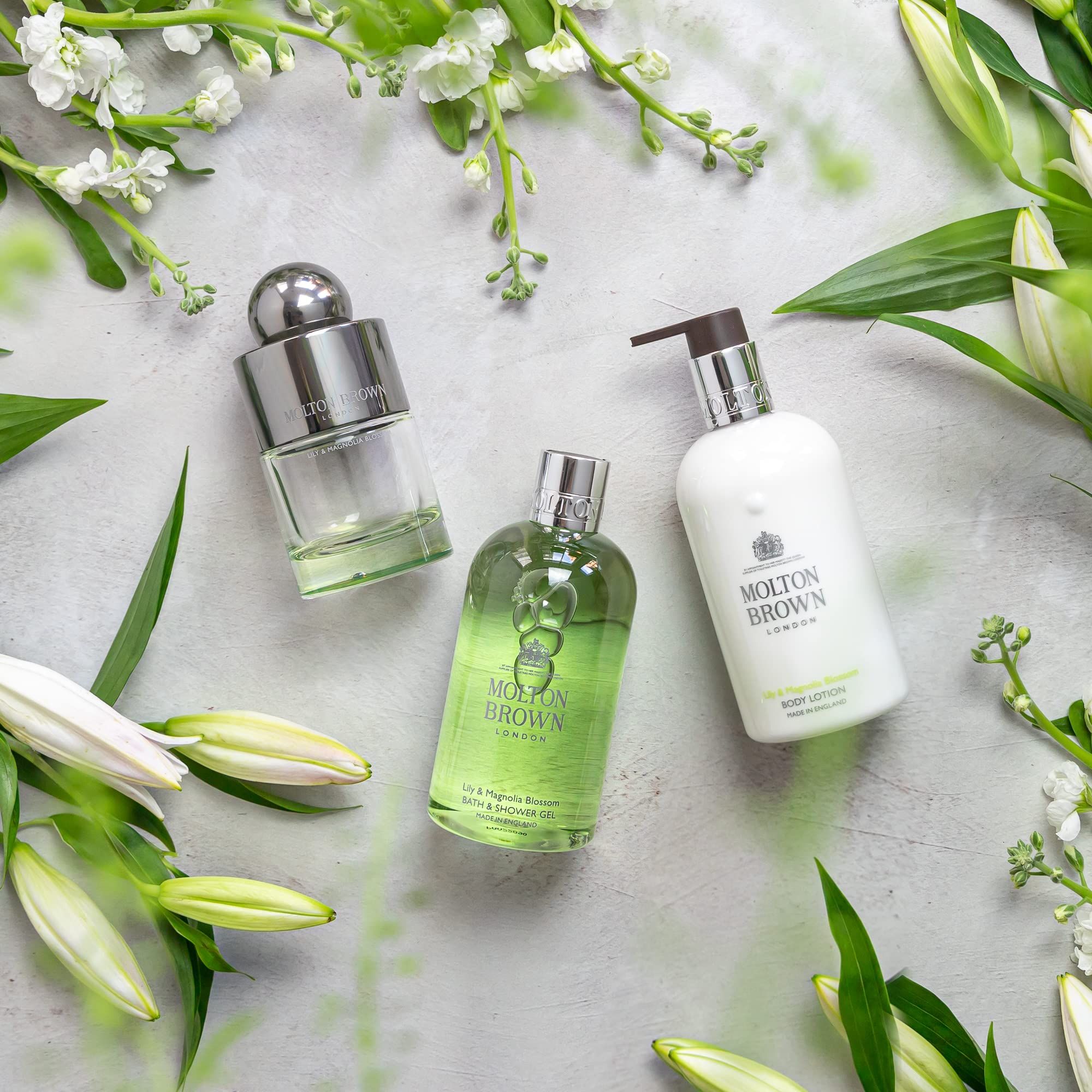 Drei Molton Brown Produkte: Eau de Toilette, Duschgel und Body Lotion. Umgeben von Blumen.
