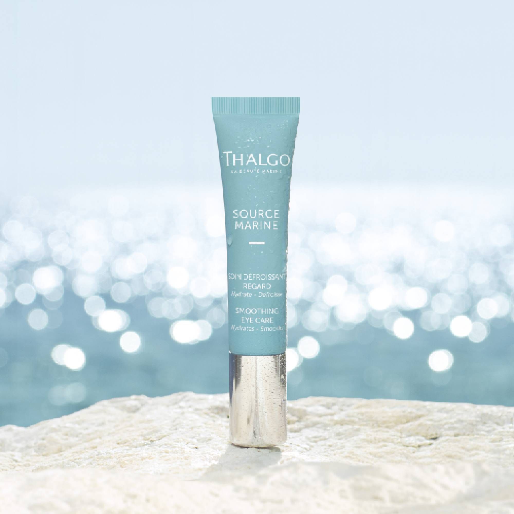 Türkisfarbene Tube mit silbernem Verschluss, vor verschwommenem Hintergrund. Aufschrift: THALGO, SOURCE MARINE, SOIN DÉFROISSANT REGARD, Smoothing Eye Care.