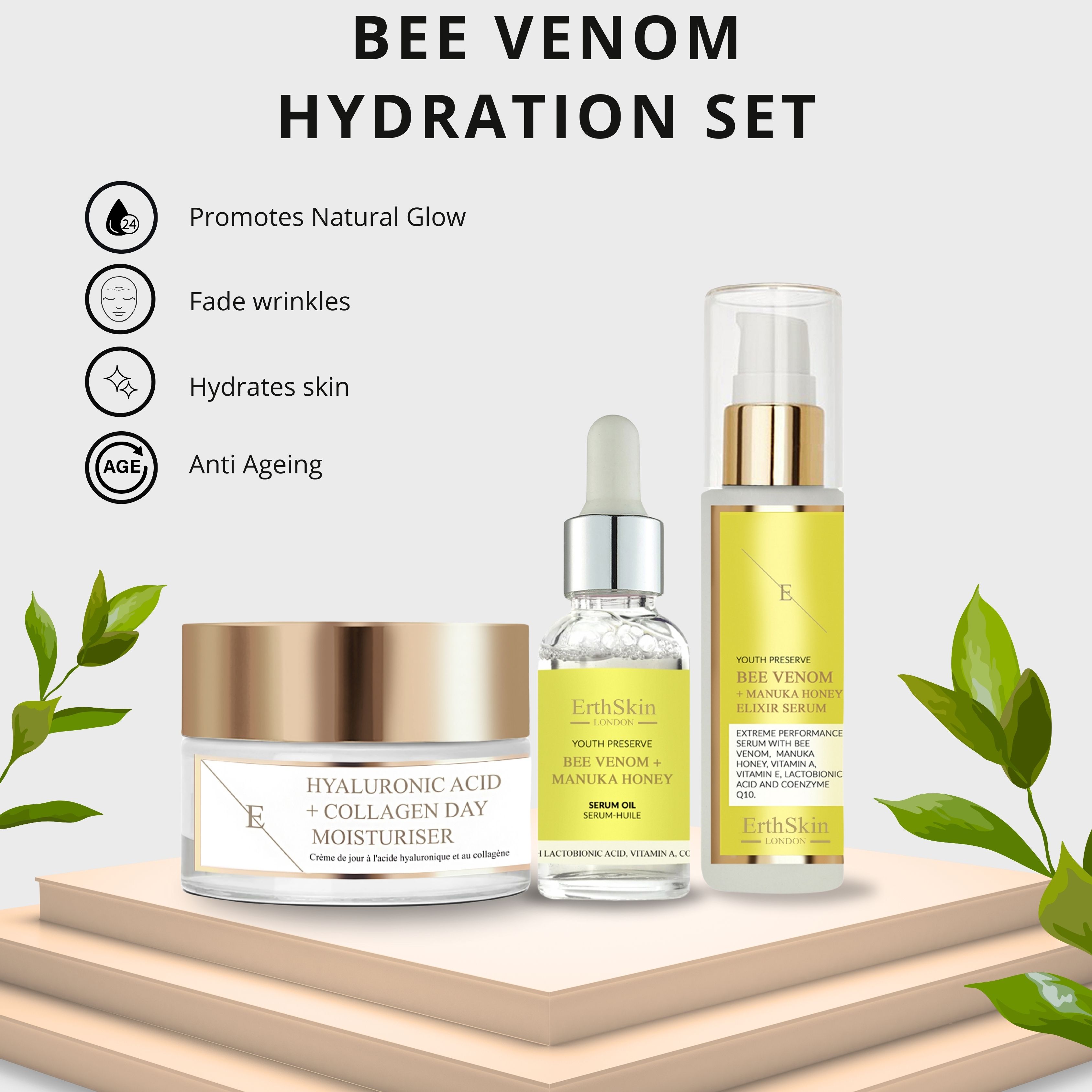 Kosmetik-Set mit Tagescreme, Serumöl und Elixier-Serum. Aufschrift: Hyaluronsäure + Kollagen, Bee Venom + Manuka Honey. Auf Podest mit Blättern.