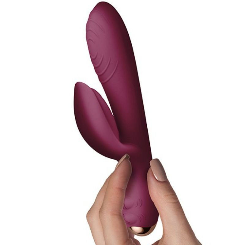 Burgunderfarbener Vibrator in einer Hand gehalten. Goldfarbener Akzent am unteren Ende.