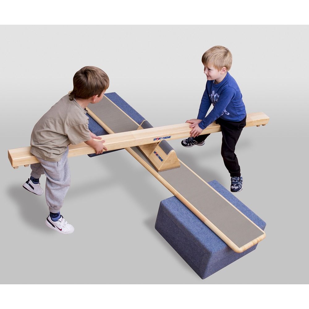 Wippbalken mit zwei Kindern. Holzkonstruktion mit blauen und grauen Elementen. Kinder balancieren und halten sich fest.