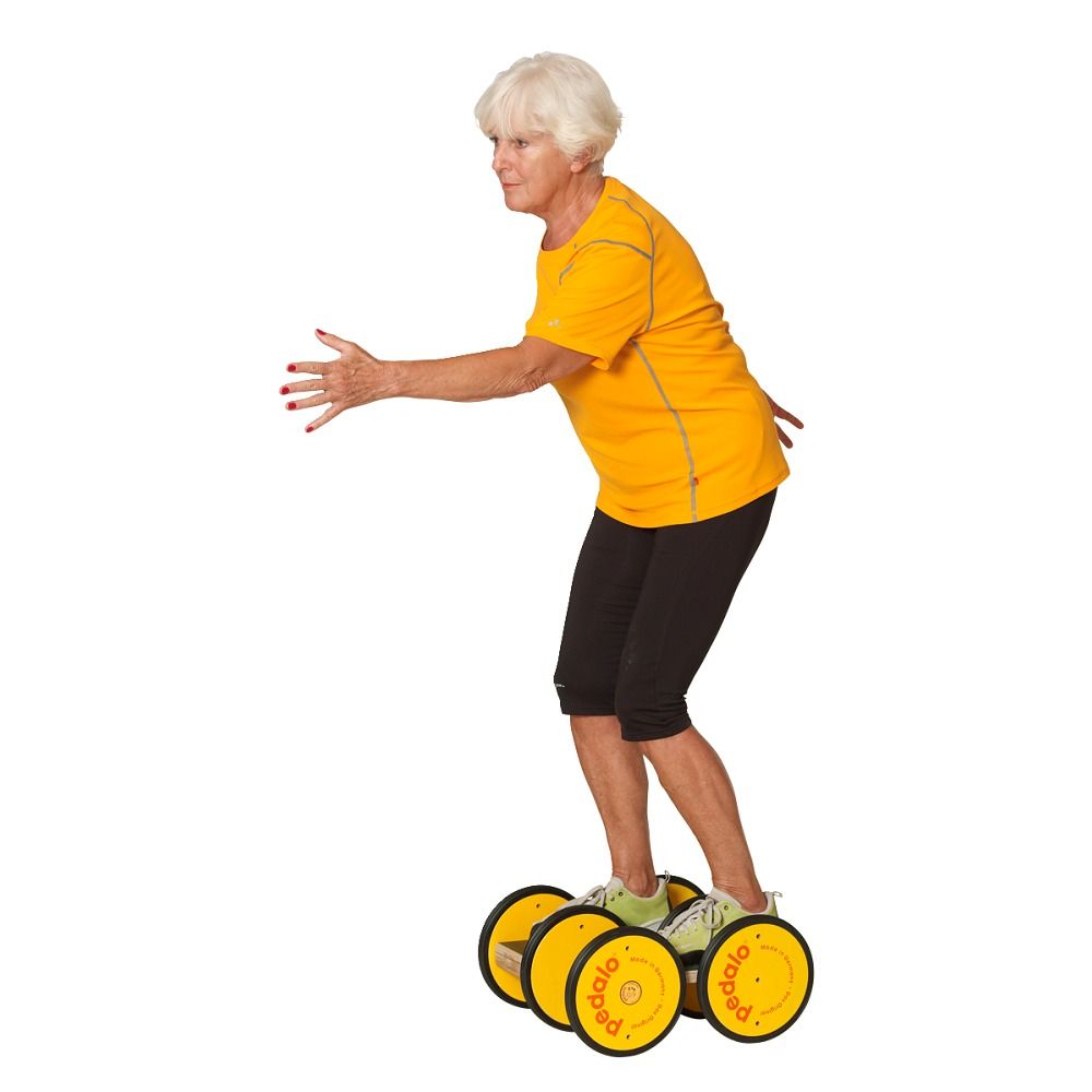 Ältere Frau auf einem Koordinationstrainer. Gelbe Räder mit "pedalo"-Logo. Sie trägt Sportkleidung und balanciert.
