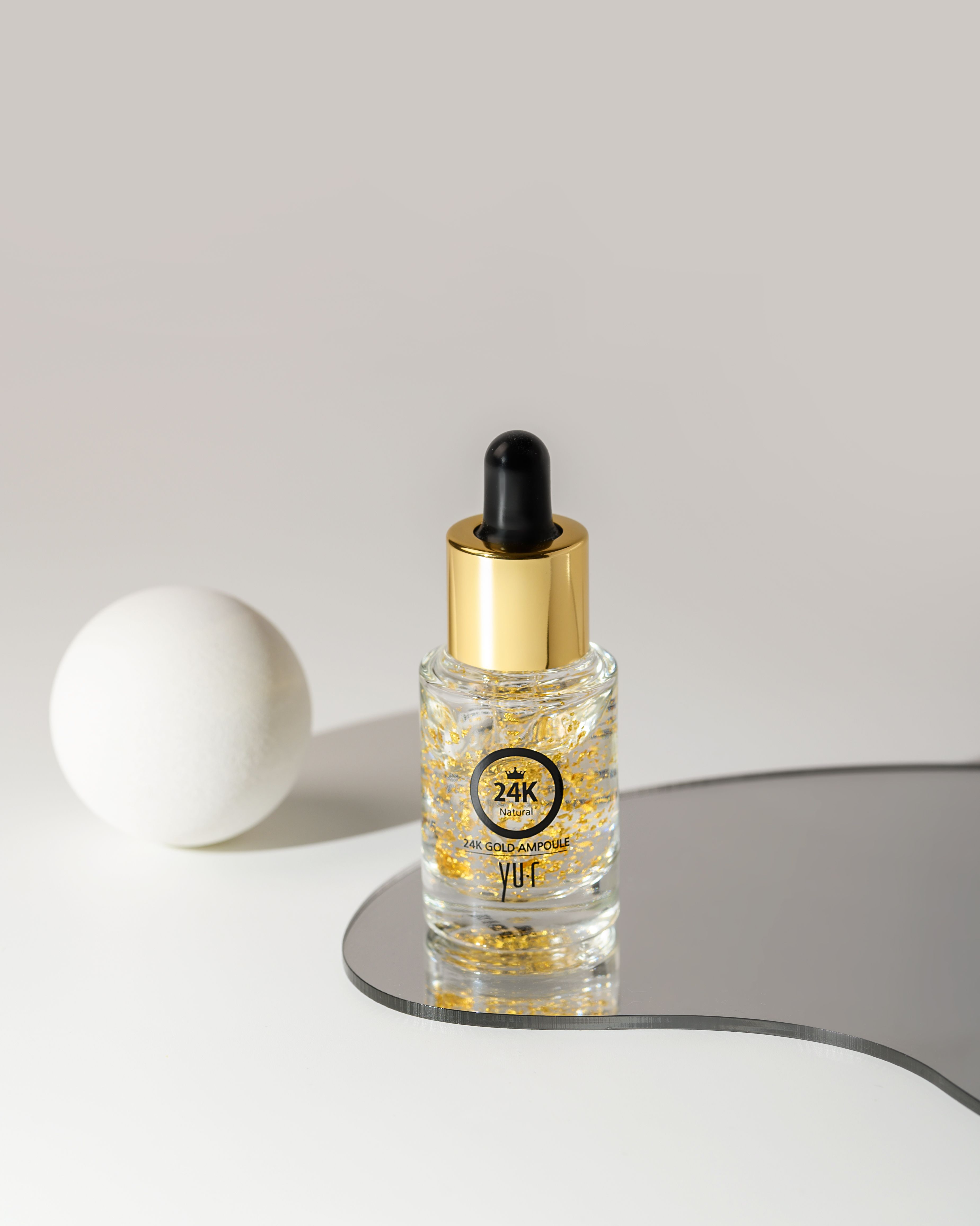 Serumflasche mit Goldflocken, schwarzer Pipette und goldener Kappe. Aufschrift: 24K Gold, Yu.R.