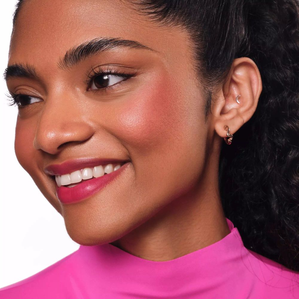 Porträt einer Frau mit rosa Lippen und Wangen. Sie trägt rosa Kleidung.