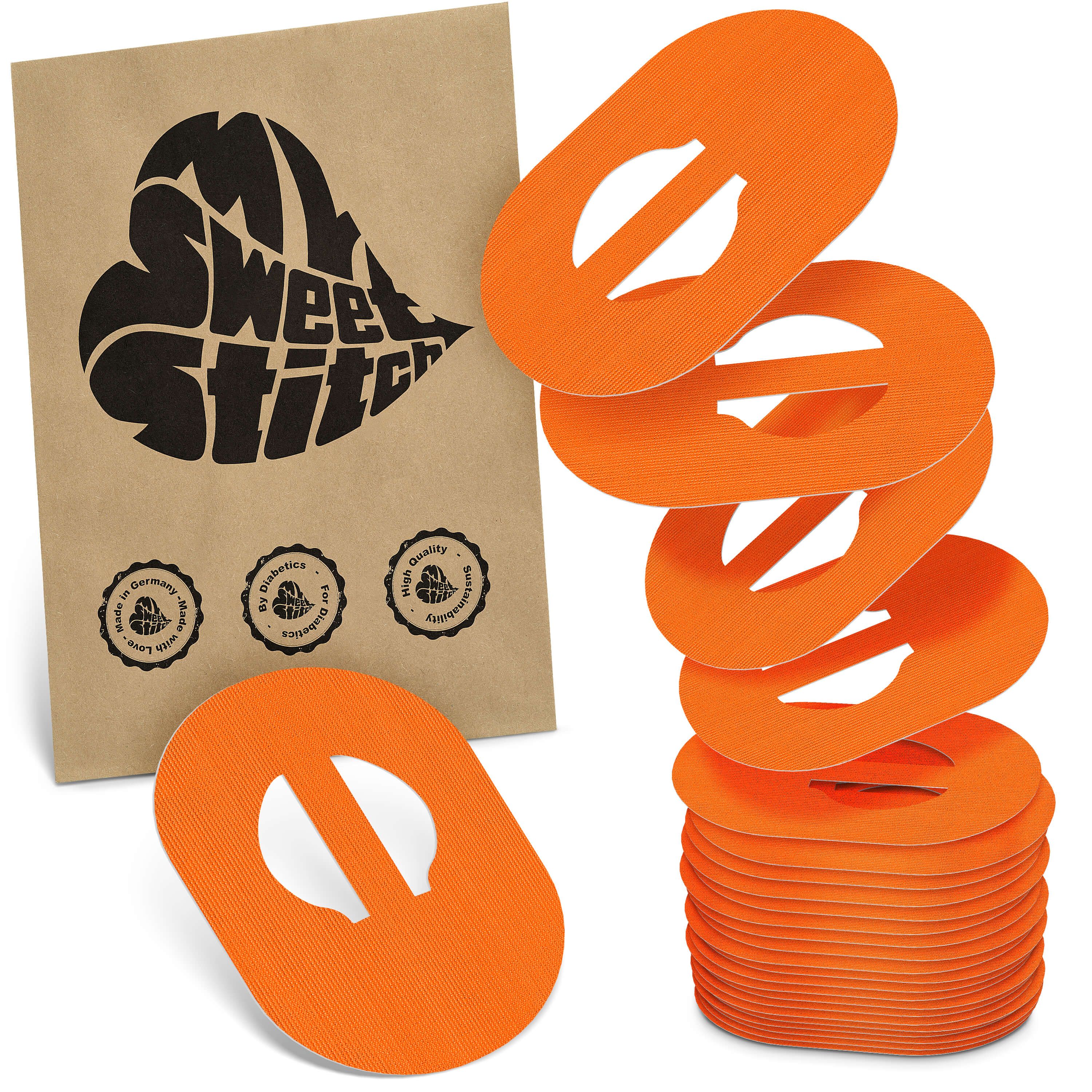 Orange, ovale Pflaster mit Ausschnitt, gestapelt und einzeln liegend, neben einer braunen Papiertüte mit schwarzem Herz-Logo.