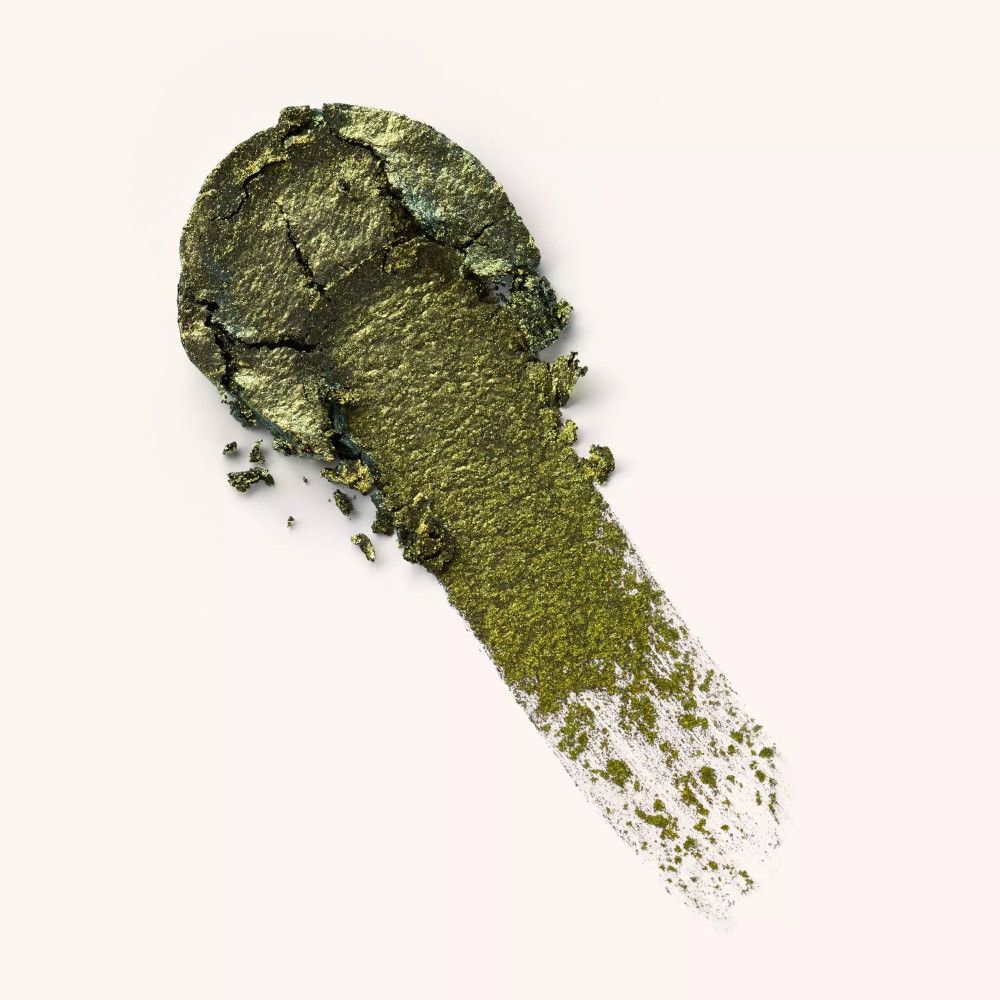 Abstrich von grün-goldenem Lidschatten auf weißem Hintergrund. Die Textur ist sichtbar.