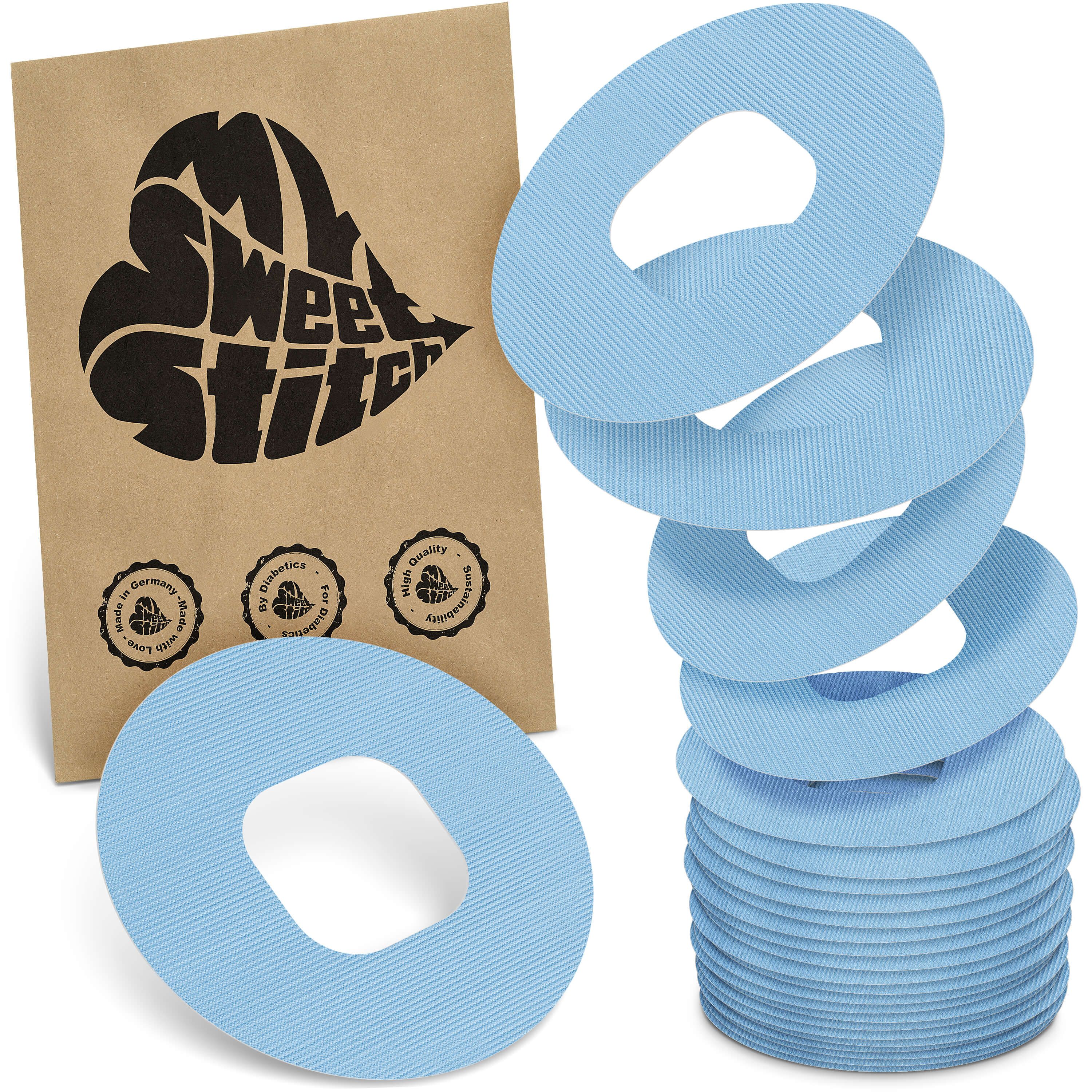 Hellblaue, ringförmige Pflaster mit Loch in der Mitte. Neben einer Verpackung mit Logo. Mehrere Pflaster gestapelt.