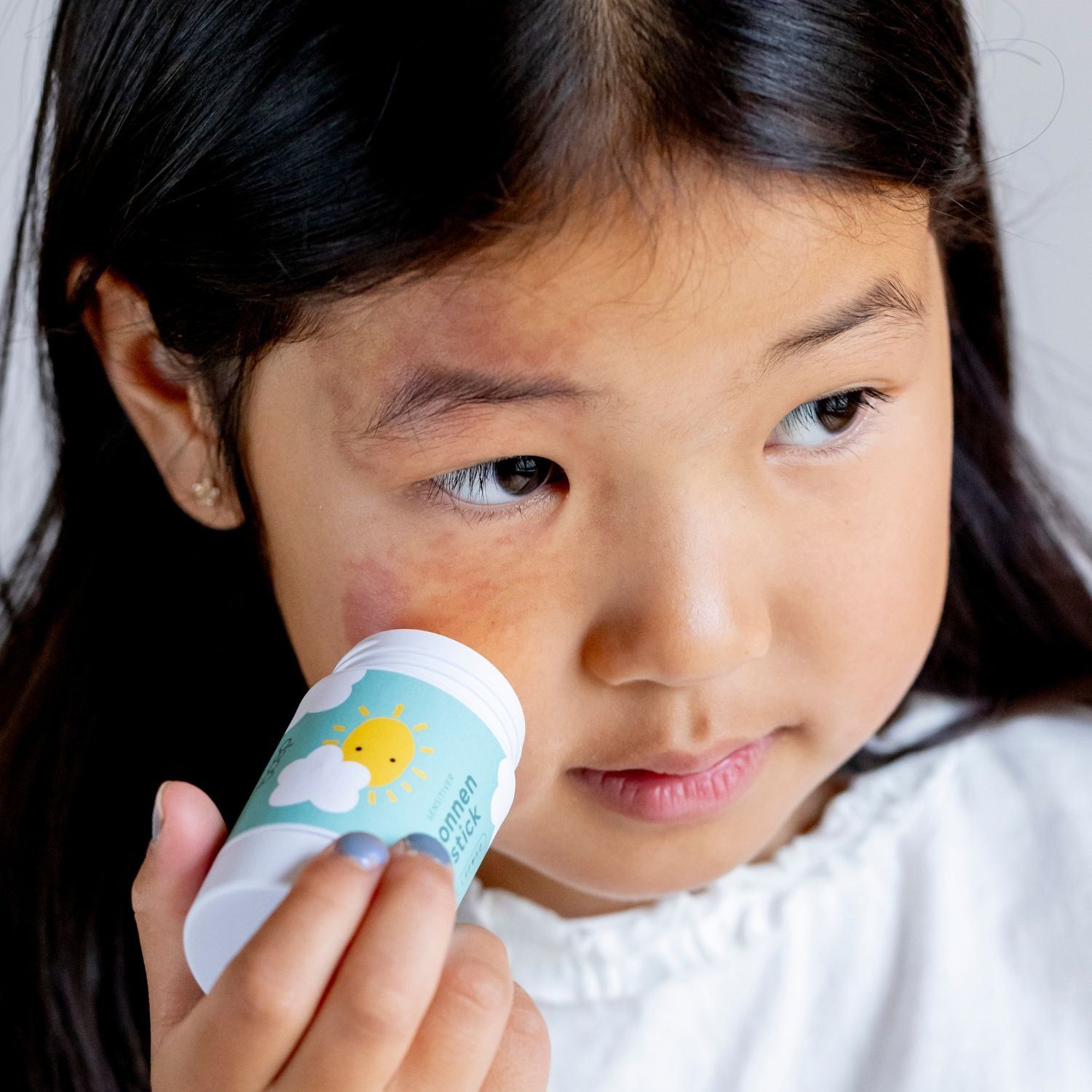 Sonnenschutzstift mit Sonne-und-Wolken-Design. Enthält Zinkoxid, Mandelöl und Vitamin E.