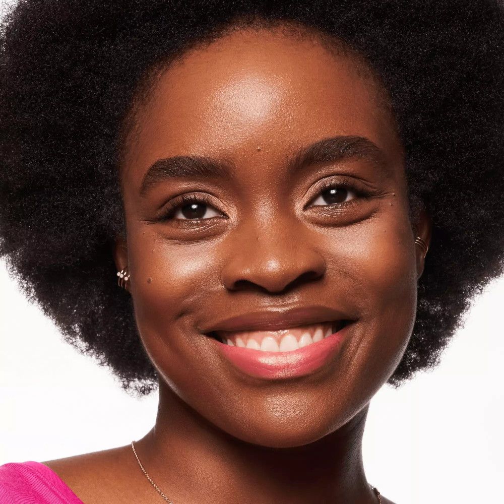Nahaufnahme eines lächelnden Gesichts. Hautton mit Make-up. Rosa Lippenstift. Halskette und Ohrringe.