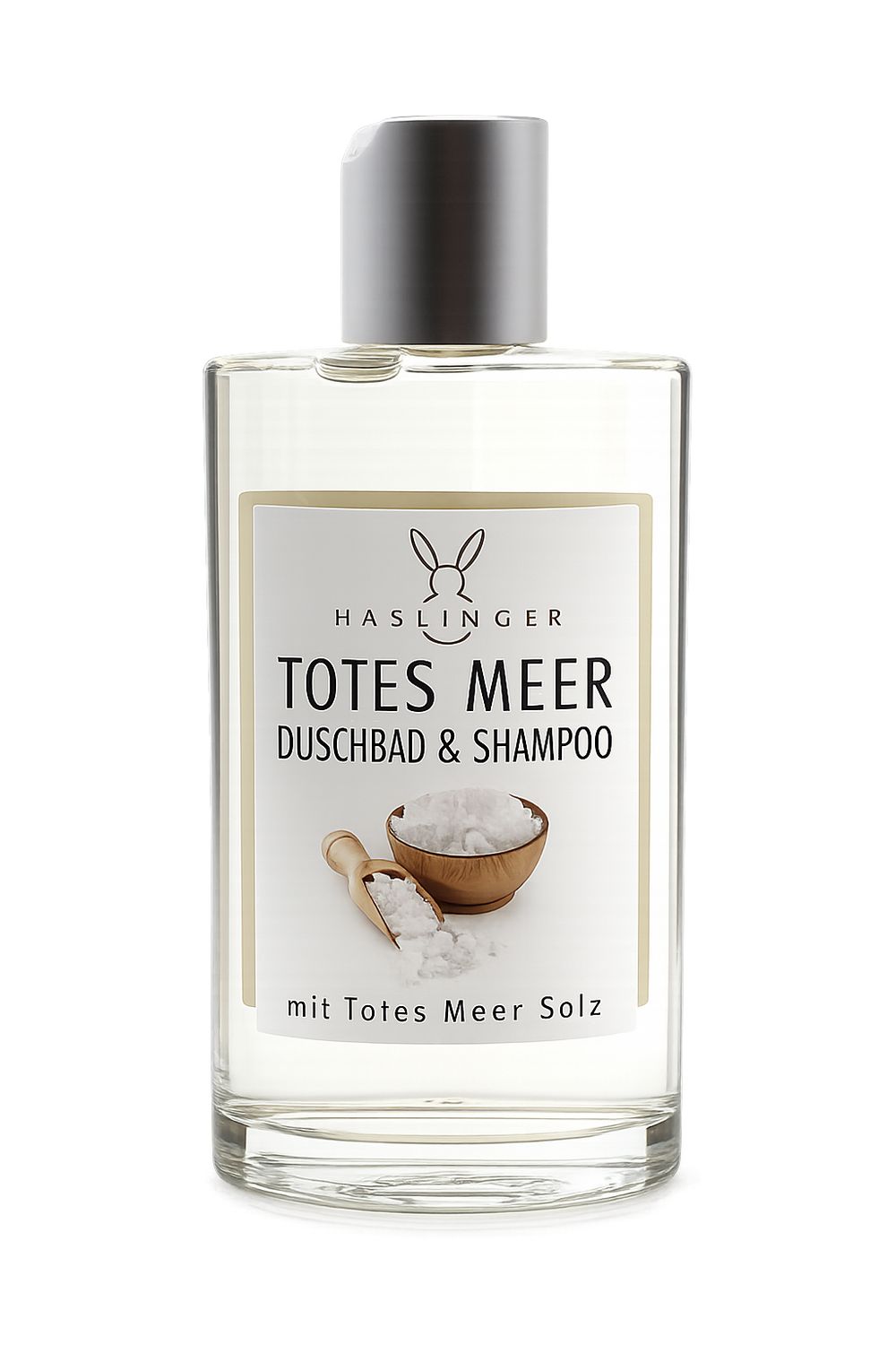 Klare Flasche mit silbernem Deckel. Etikett mit Produktnamen und Abbildung von Salz. Text: Totes Meer Duschbad & Shampoo.