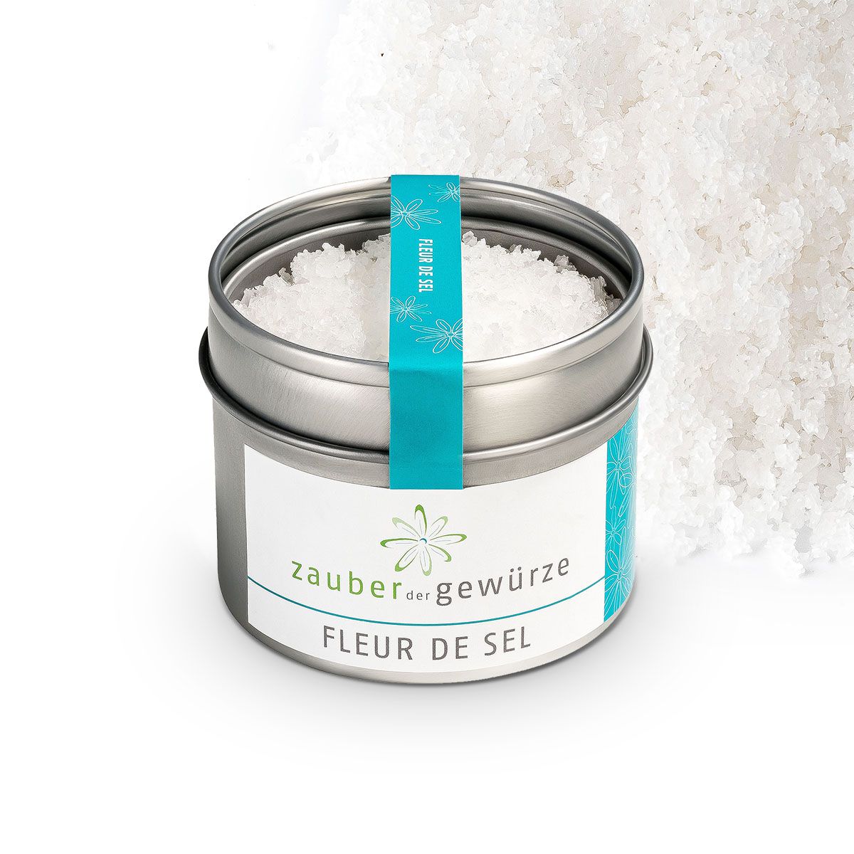 Runde Dose mit Fleur de Sel. Aufschrift: Zauber der Gewürze, Fleur de Sel. Türkisfarbenes Band mit Blumenmuster.