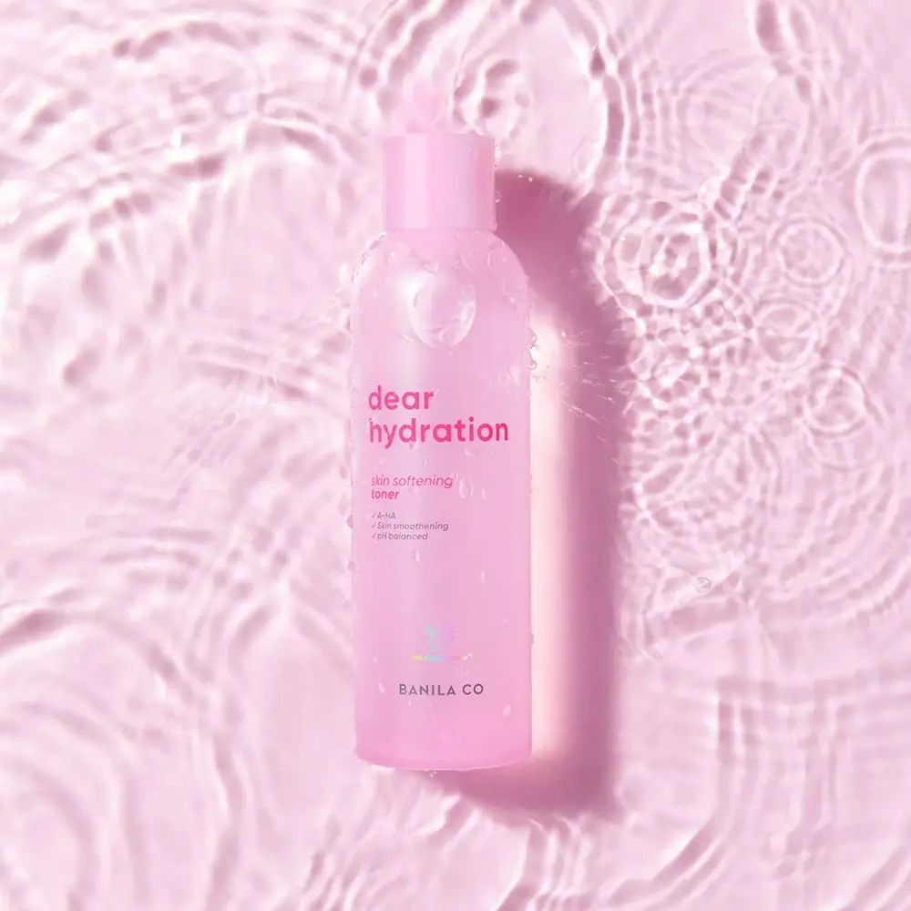 Rosa Flasche mit "dear hydration"-Aufdruck im Wasser. Text: "skin softening toner", "A-HA", "pH balanced". Marke: BANILA CO.