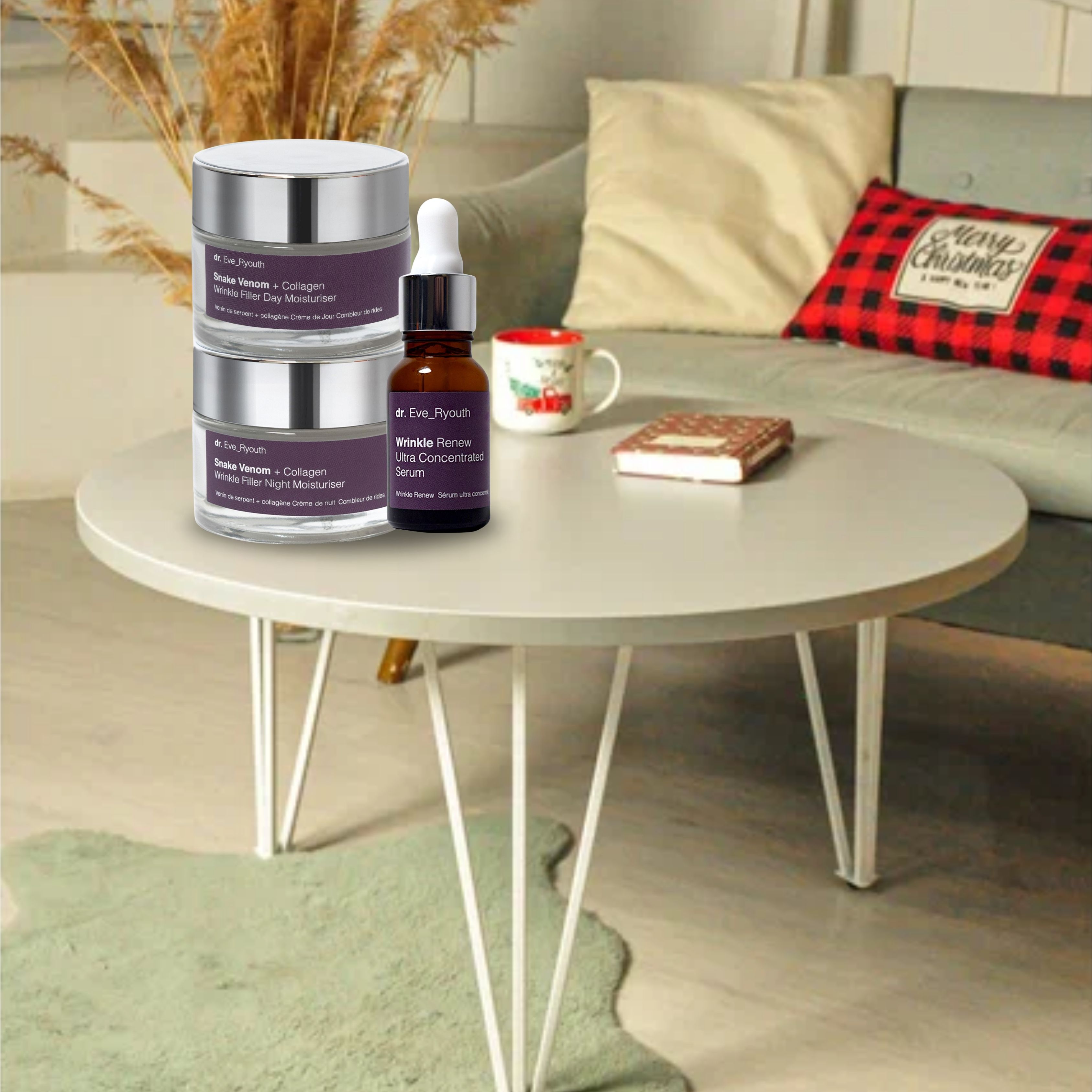 Das Dr. Eve_Ryouth Set auf einem Tisch. Zwei Cremetiegel und eine Serumflasche. Im Hintergrund: Sofa, Kissen, Tasse, Buch.