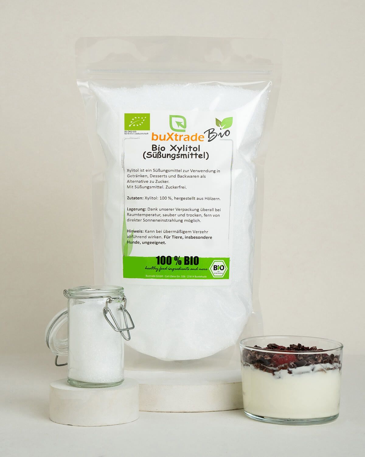 Bio Xylitol Süßungsmittel in einem Beutel, daneben ein Glas mit Xylitol und ein Dessert.