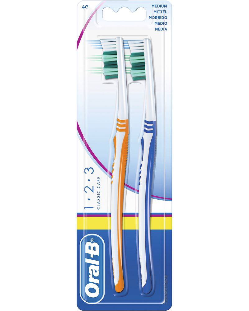 Zwei Zahnbürsten in Blisterverpackung. Orange und blaue Griffe. "Oral-B 1.2.3 Classic Care". Borsten grün. "Medium".