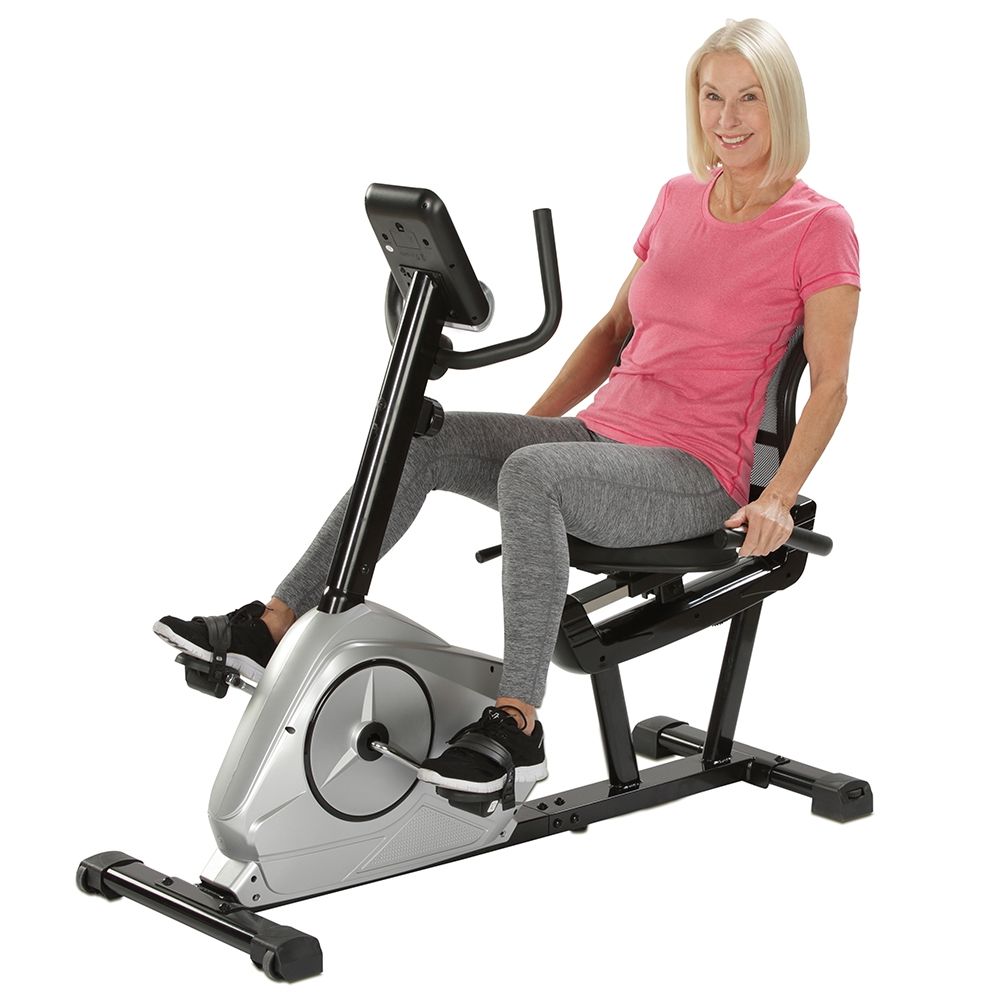 Frau sitzt auf einem Sitz-Heimtrainer. Sie trägt Sportkleidung. Das Gerät ist in Betrieb.