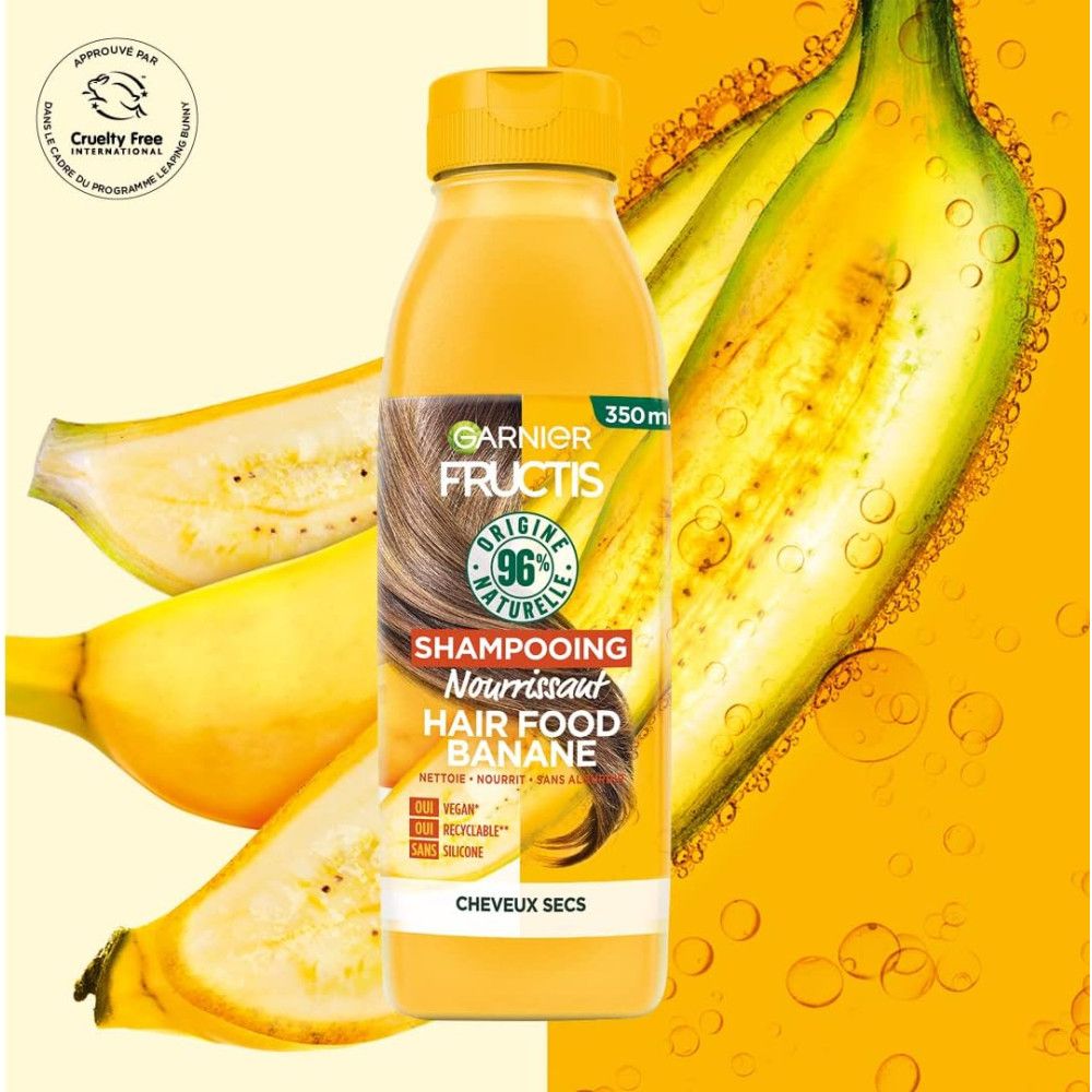 Gelbe Flasche mit Garnier Fructis Shampoo. Aufschrift: Hair Food Banane, 96% natürliche Inhaltsstoffe. Vegan, recycelbar, ohne Silikone. Mit Bananen.