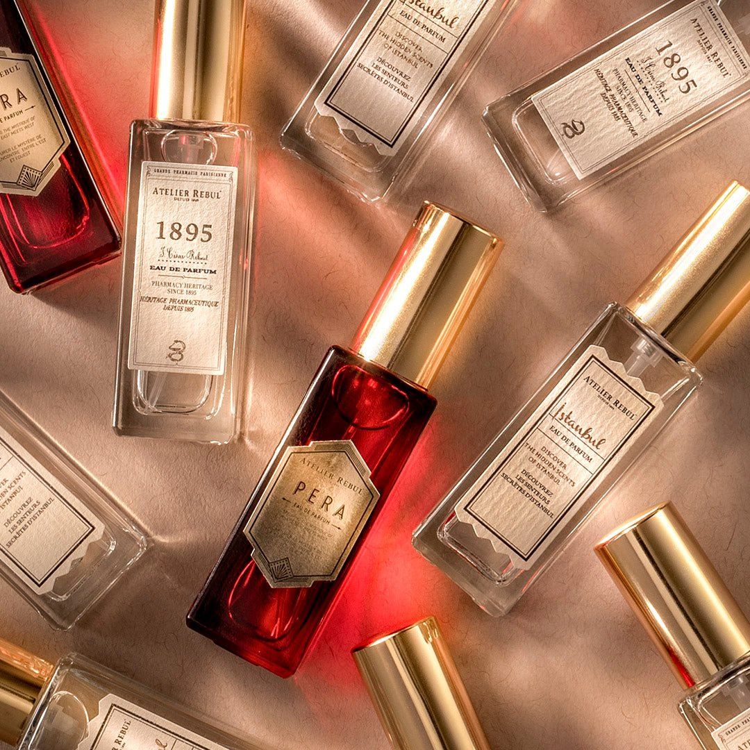 Mehrere Parfümfläschchen mit goldenen Verschlüssen und Etiketten. Rotes Fläschchen im Zentrum.