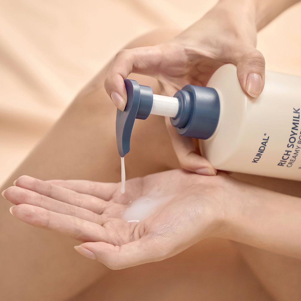 Person gießt Flüssigkeit aus einer Flasche in die Hand. KUNDAL Rich Soymilk ist sichtbar.