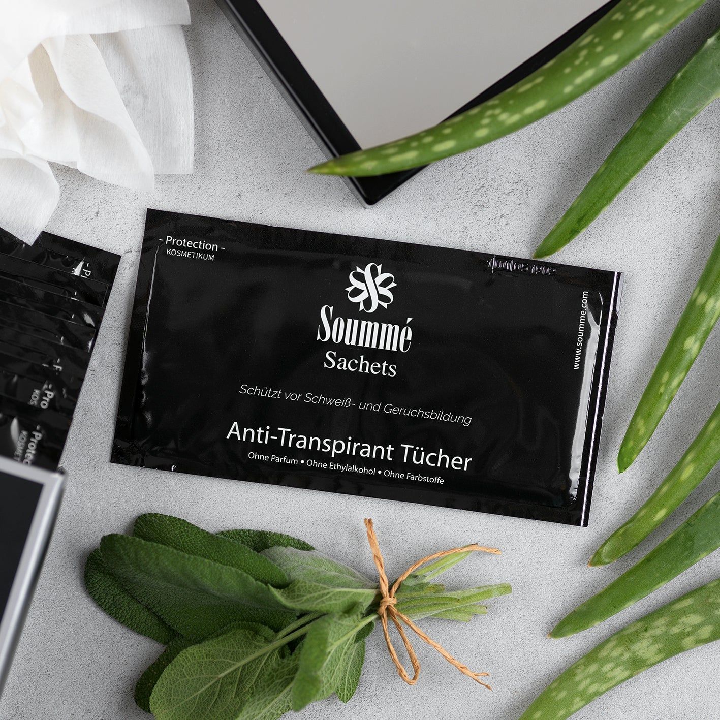 Soummé Antitranspirant Sachet auf einem Tisch mit Kräutern und Aloe Vera.