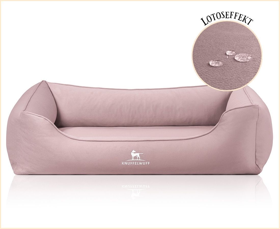 Orthopädisches Hundebett in Rosa mit Logo. Detailansicht zeigt wasserabweisende Oberfläche. Abgerundete Form mit erhöhten Seiten.
