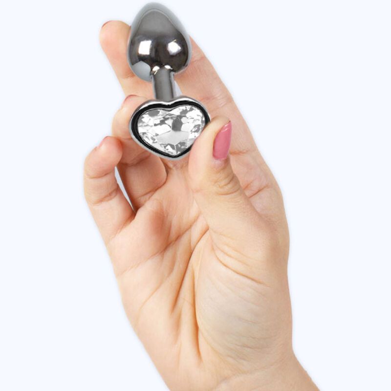 Metall-Butt Plug mit Kristallherz, gehalten in einer Hand. Herzförmiger Aufsatz und Basis. Glänzendes Metall.