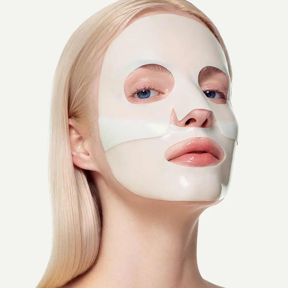 Gesichtsmaske auf Gesicht einer Frau. Aussparungen für Augen, Nase und Mund. Helle Haut, blonde Haare.