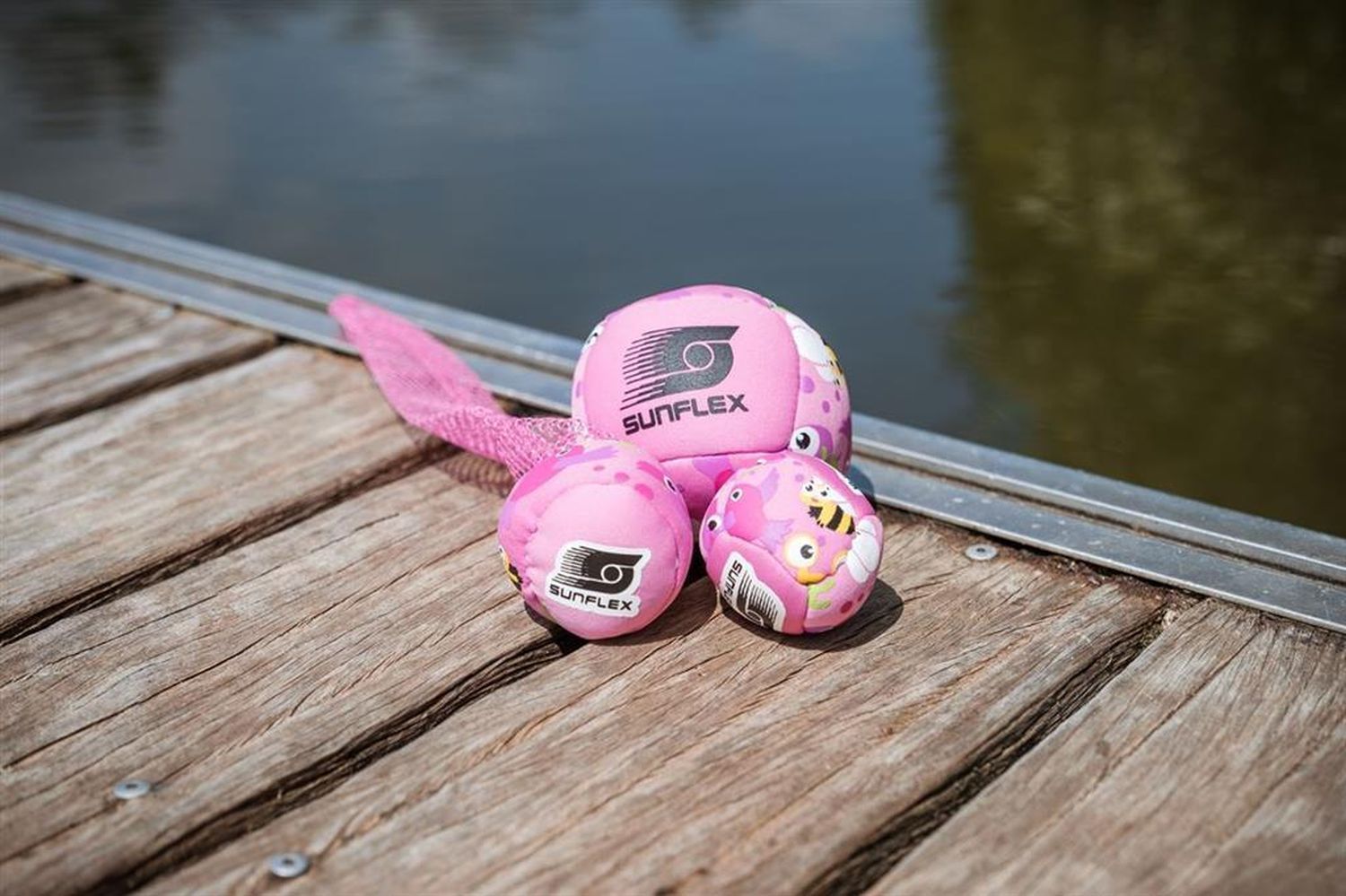 Drei pinke Wurfball-Sets auf Holz. Auf den Bällen steht SUNFLEX. Die Bälle sind mit Vögeln und Bienen bedruckt.